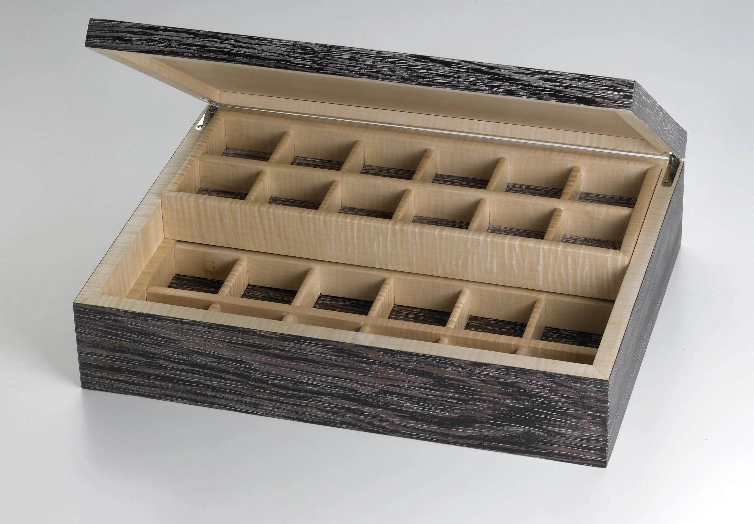 A wooden organizer with multiple compartments, featuring a black and white striped pattern on the top and dark wooden stripes on the sides, positioned against a plain white background.