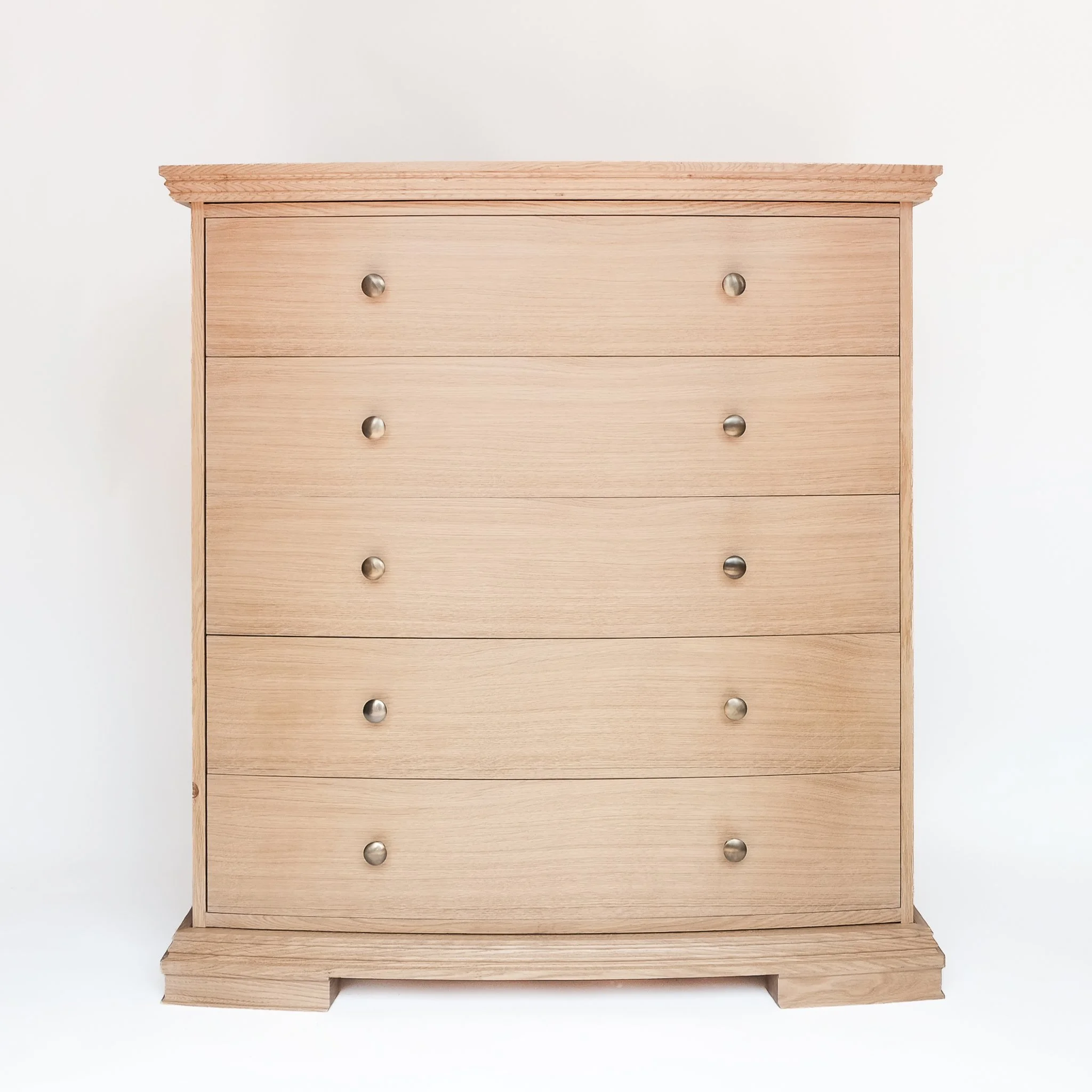 Wooden dresser with six drawers and round metal knobs, placed on a wooden base against a white background.