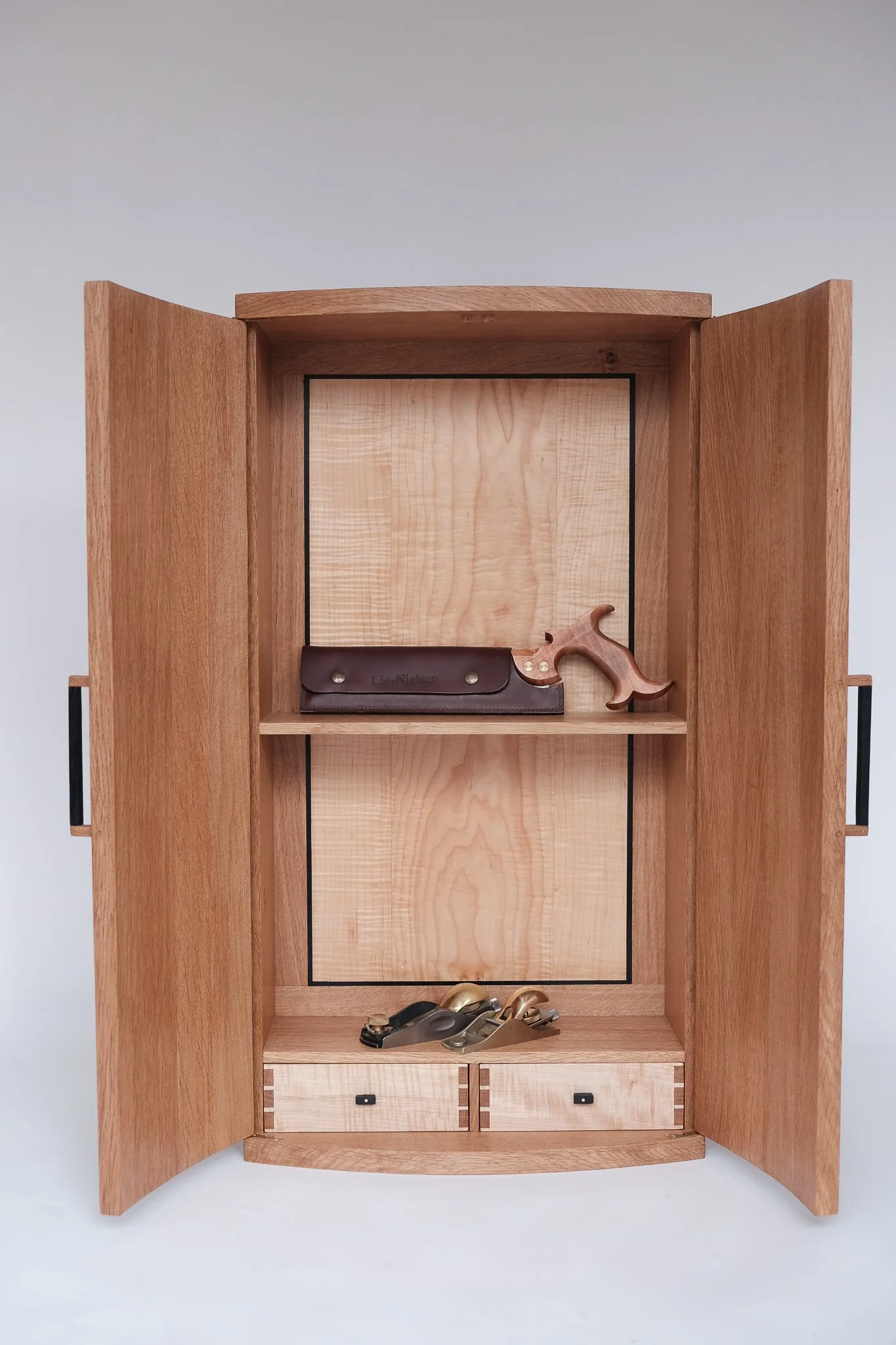 Open wooden cabinet containing leather tools, scissors, and small drawers.