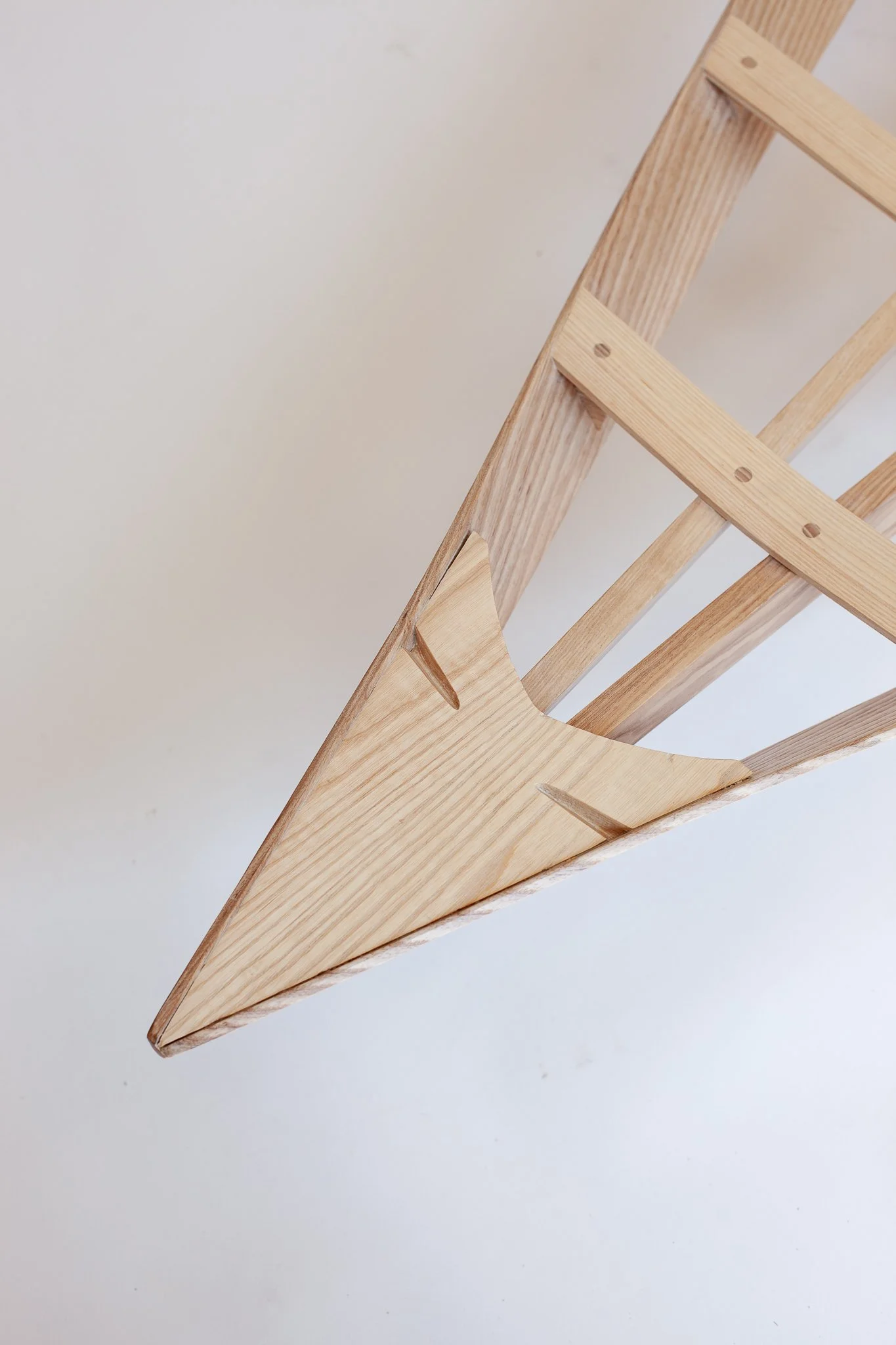 Close-up of a wooden structure with angled and interconnected pieces on a white background.