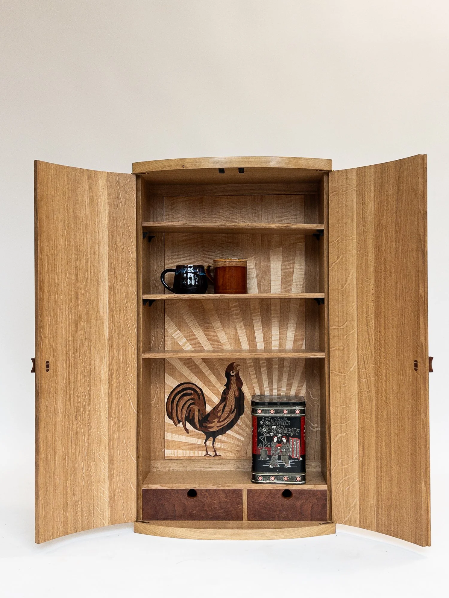 Open wooden cabinet with a rooster illustration and Japanese-themed decorative box inside.