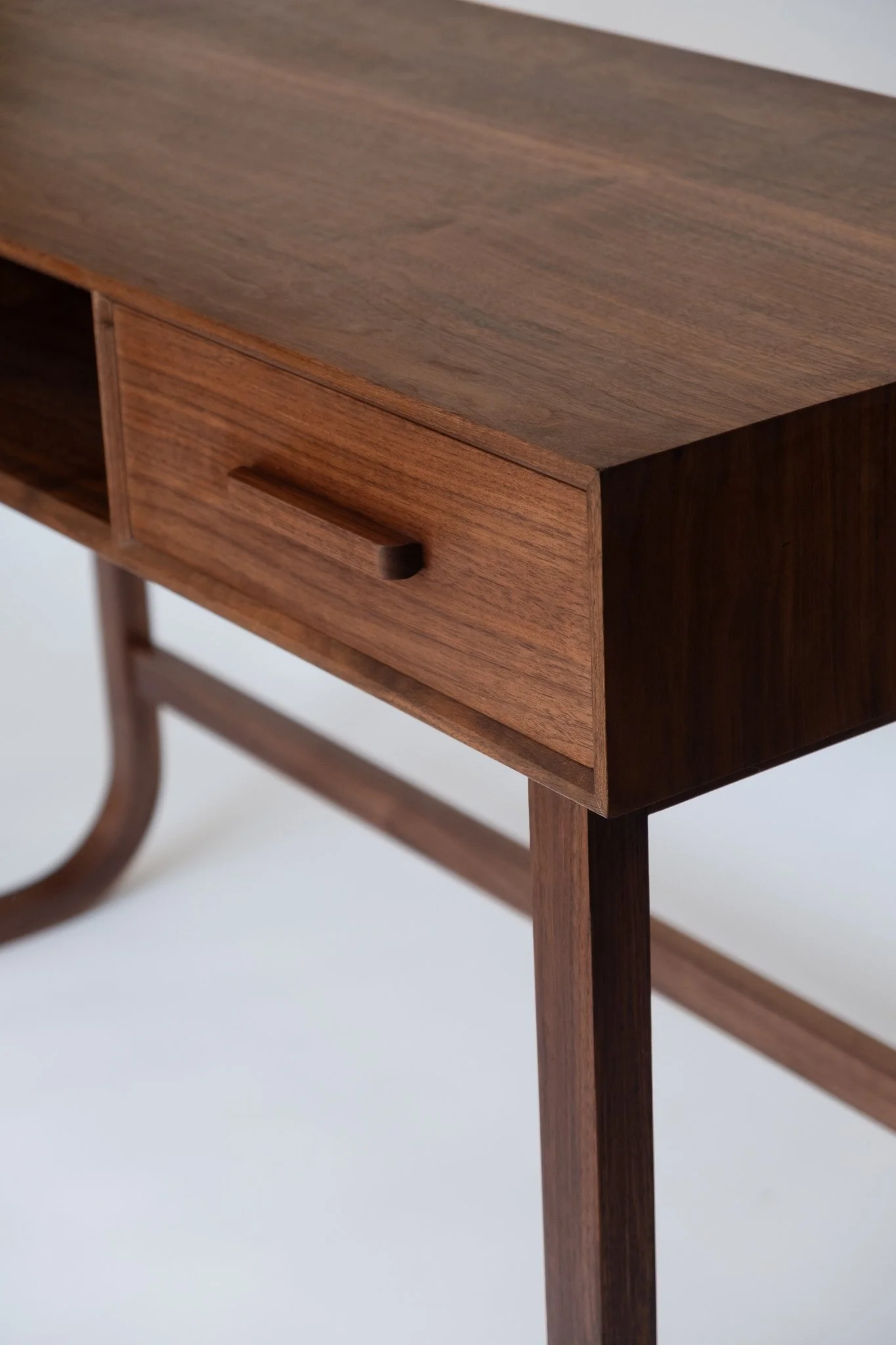 Close-up of a wooden side table with a drawer, made of dark and medium brown wood, with a simple, modern design.