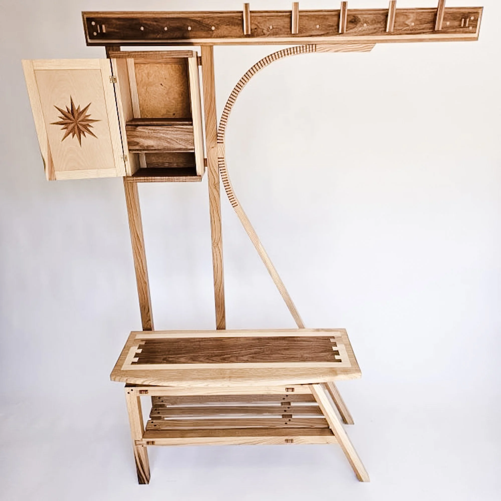 A wooden shelving unit with three shelves, a top section with a decorative inlay of a star or starburst pattern, and vertical supports.