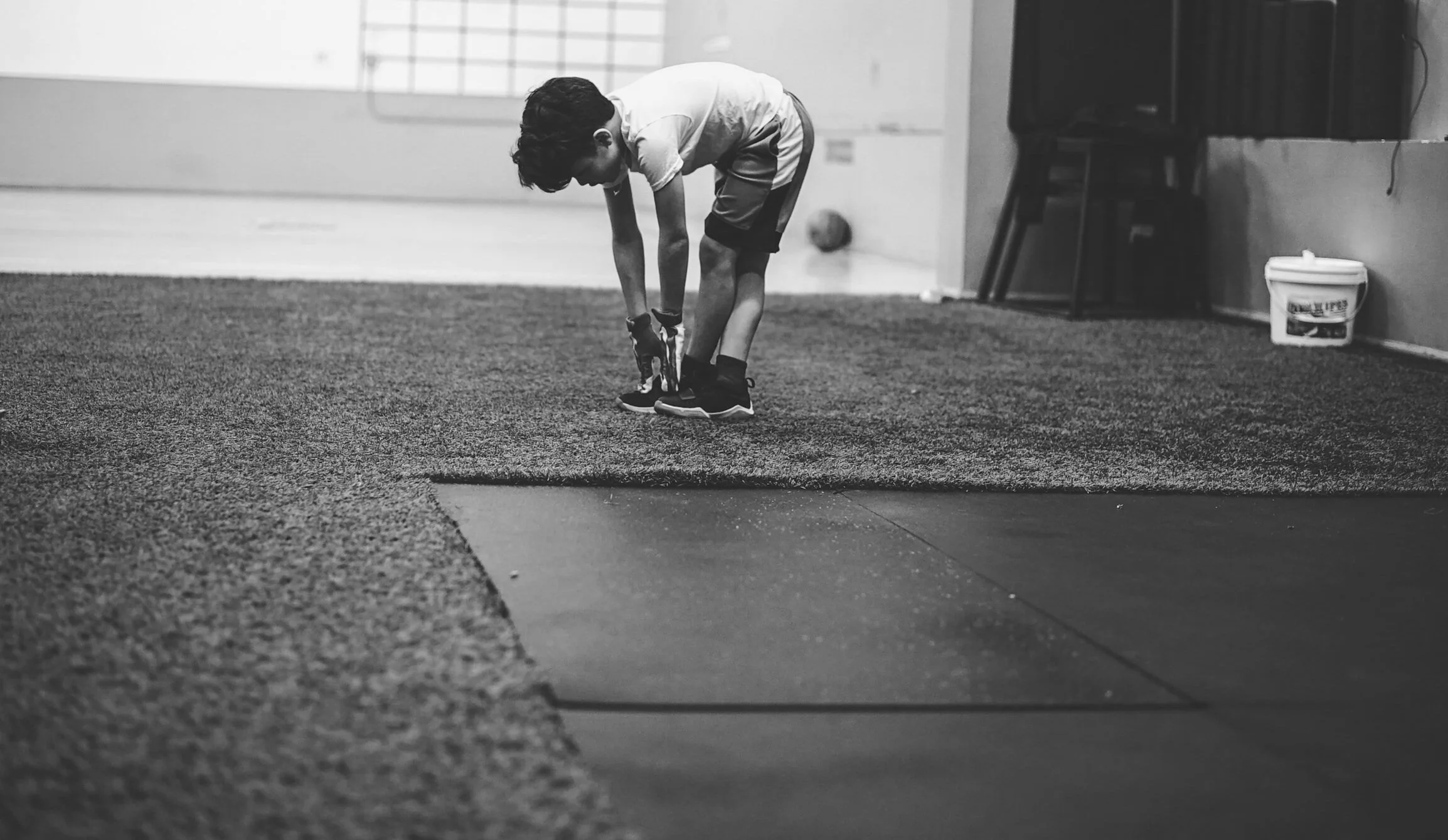 Young boy reaching his toes stretching in a gym-like setting