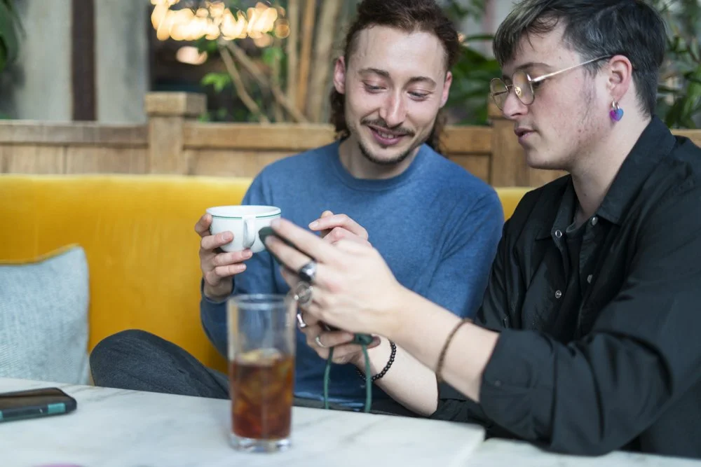 La communication pour freelance atypiques. Ethique, safe et inclusive. LGBT friendly. Freelance utilisant un ordinateur portable sur une table avec un verre de boisson.