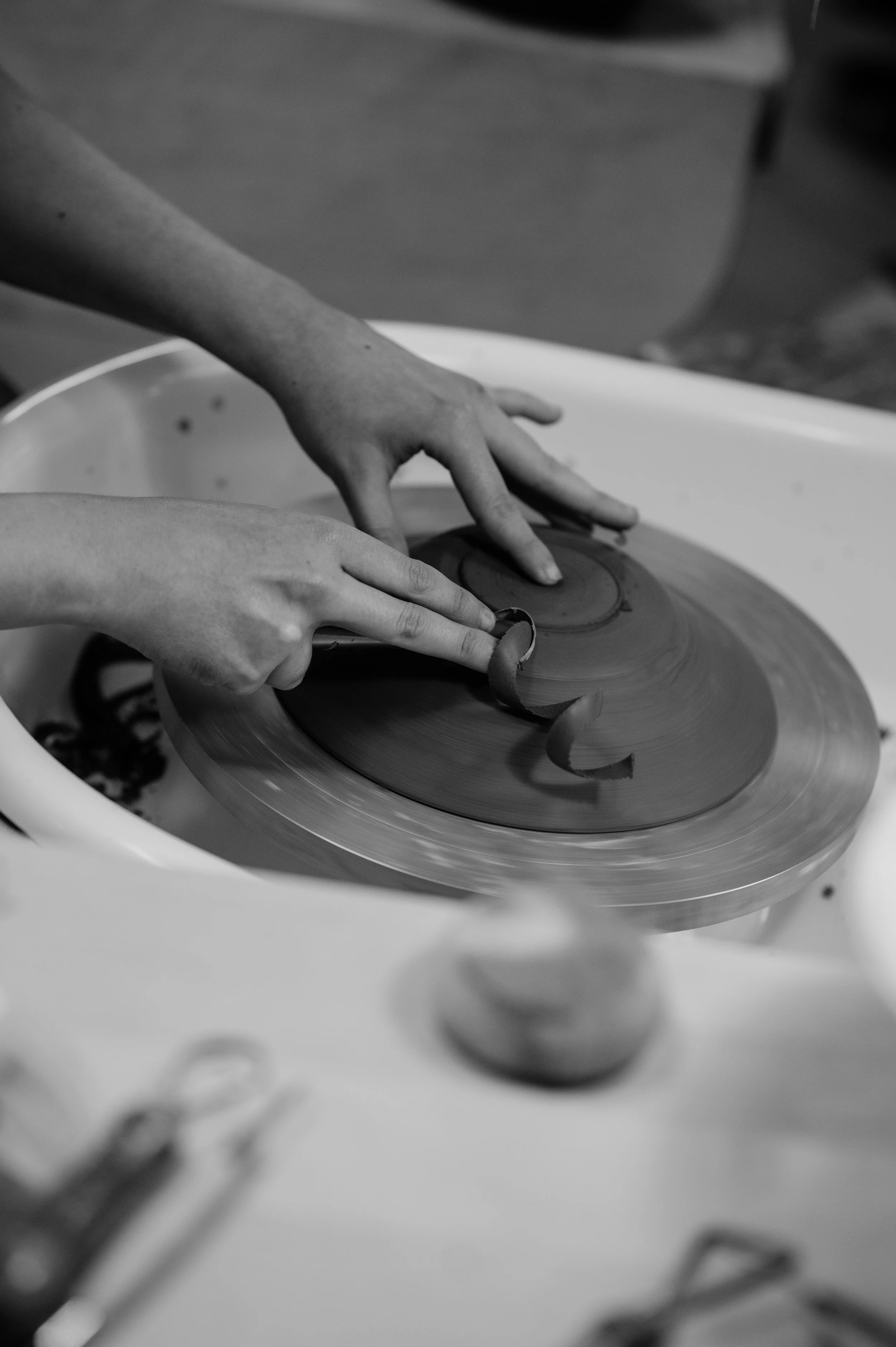 Hands shaping a piece of pottery on a spinning pottery wheel.