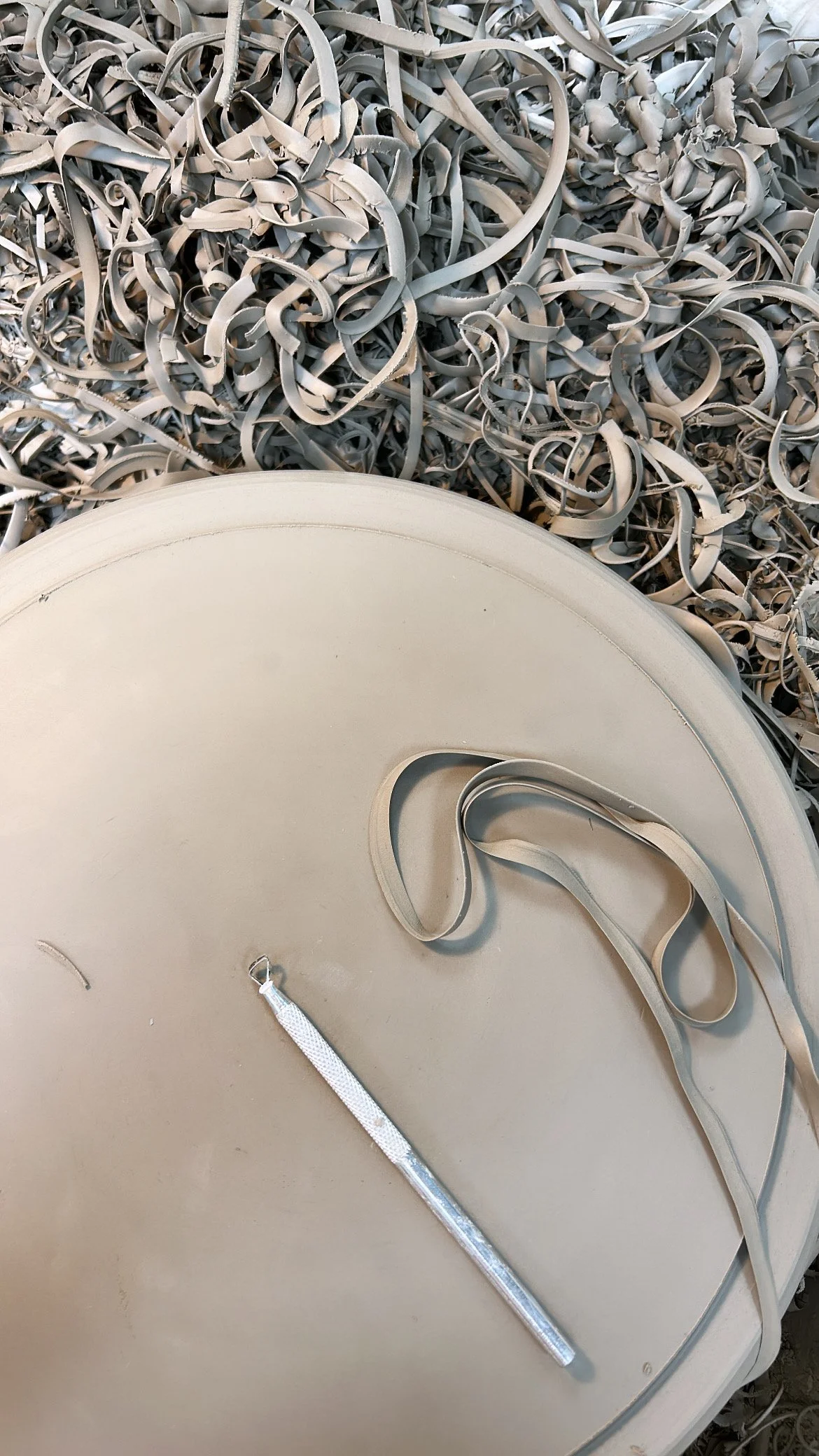 A large metal disc with a tool resting on it, surrounded by a pile of metal shavings or curls.