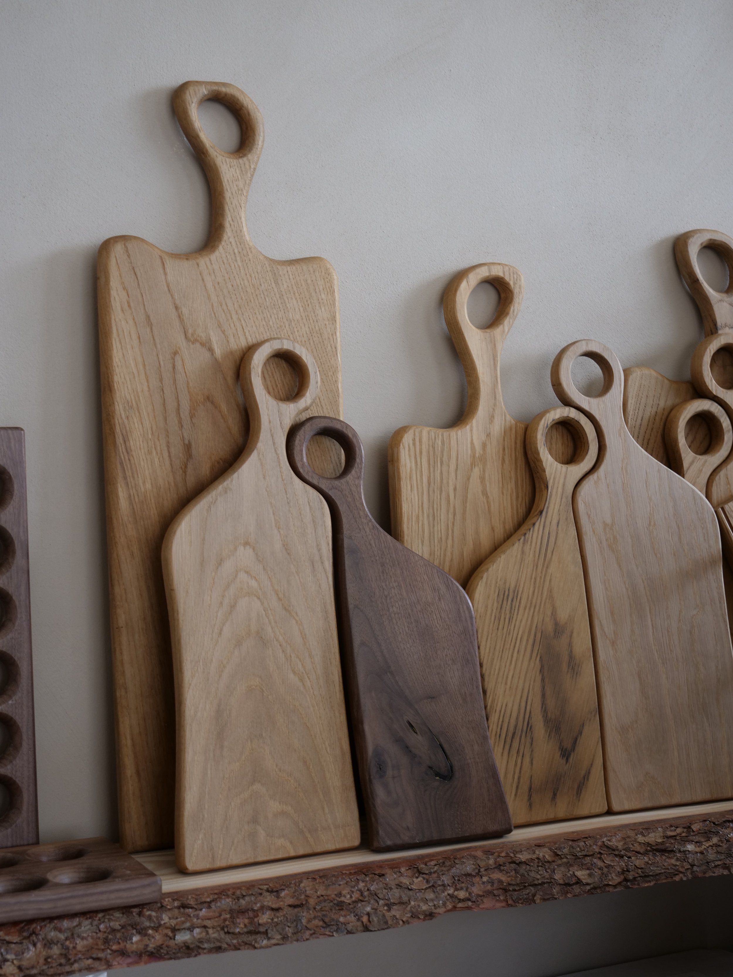 Various wooden cutting boards with circular handles, displayed on a shelf.