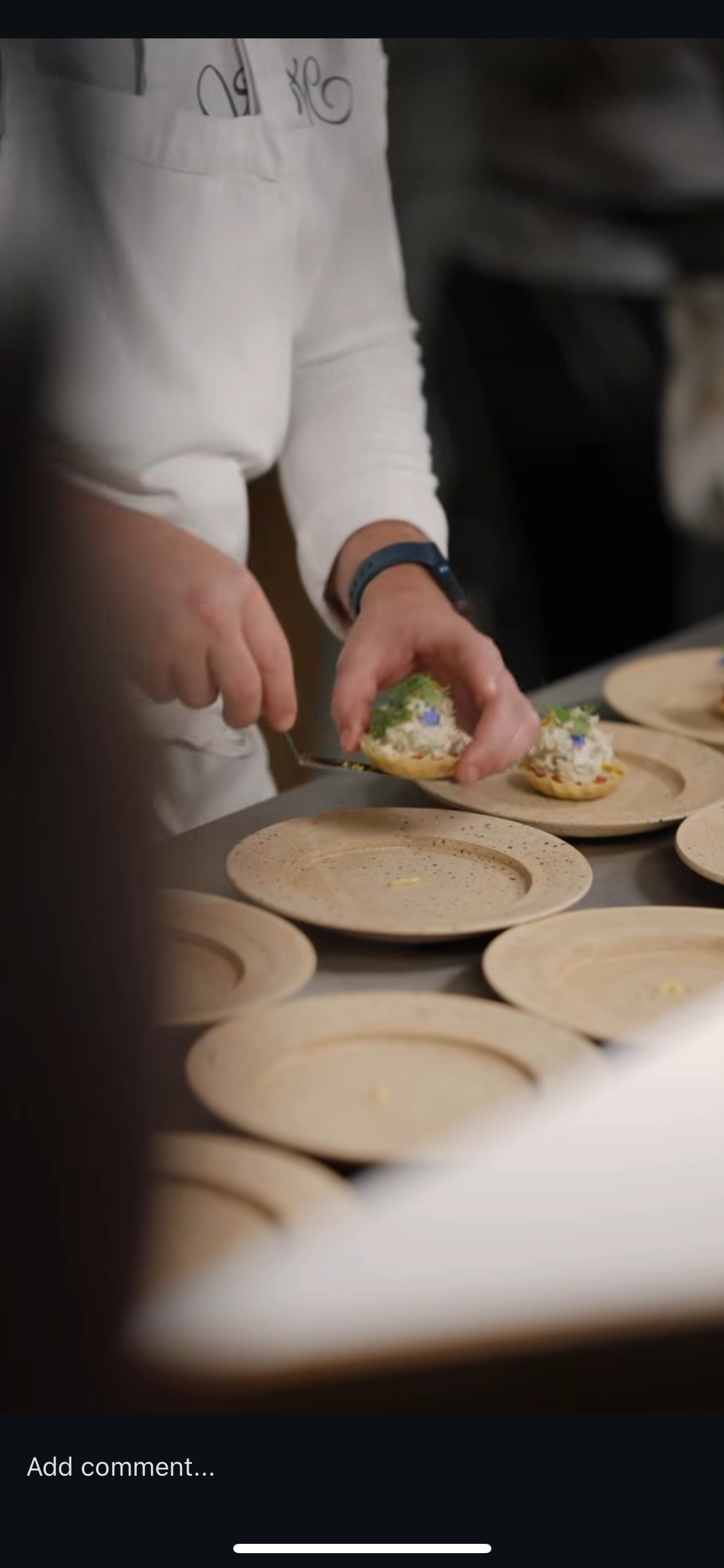 Person preparing decorated sugar cookies on a beige plate with a uniform and watch.