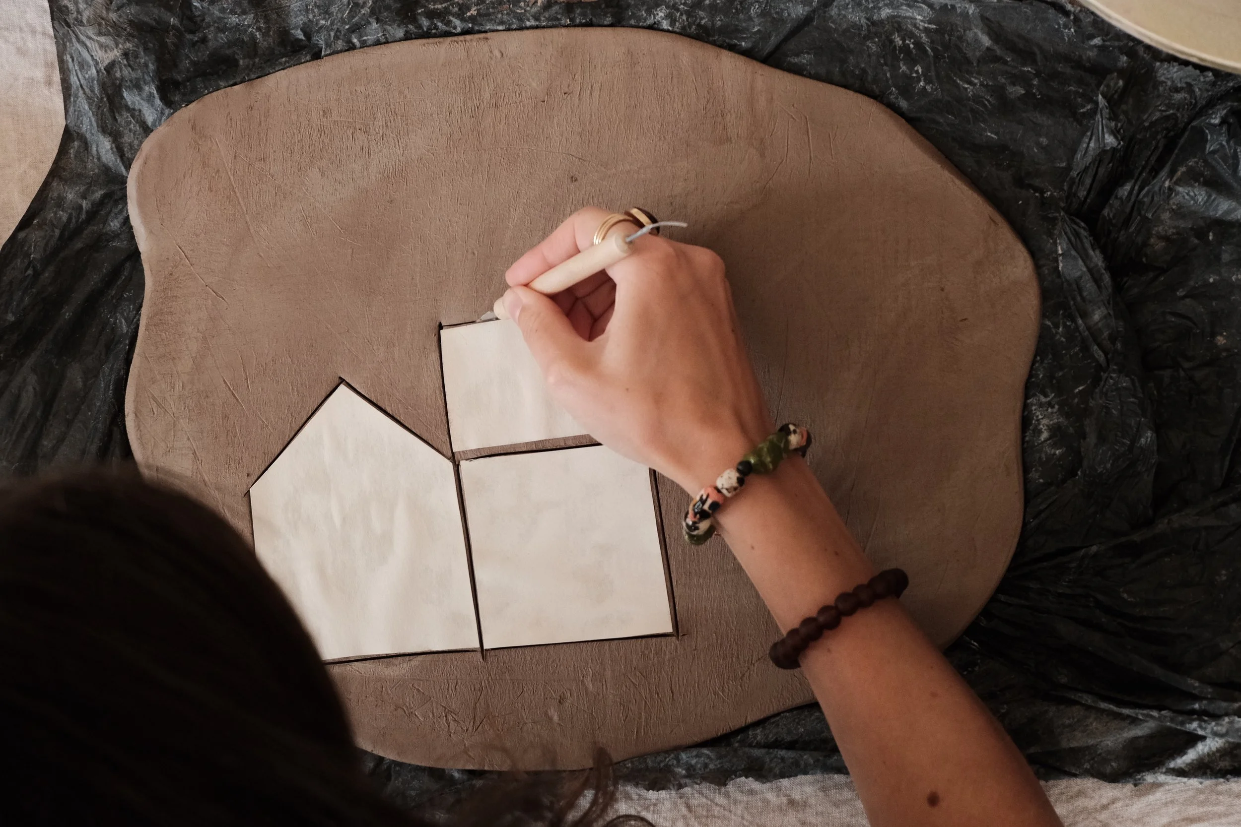 A person holding a white ceramic or porcelain object while a needle applies green adhesive or paint to a specific area of the object.