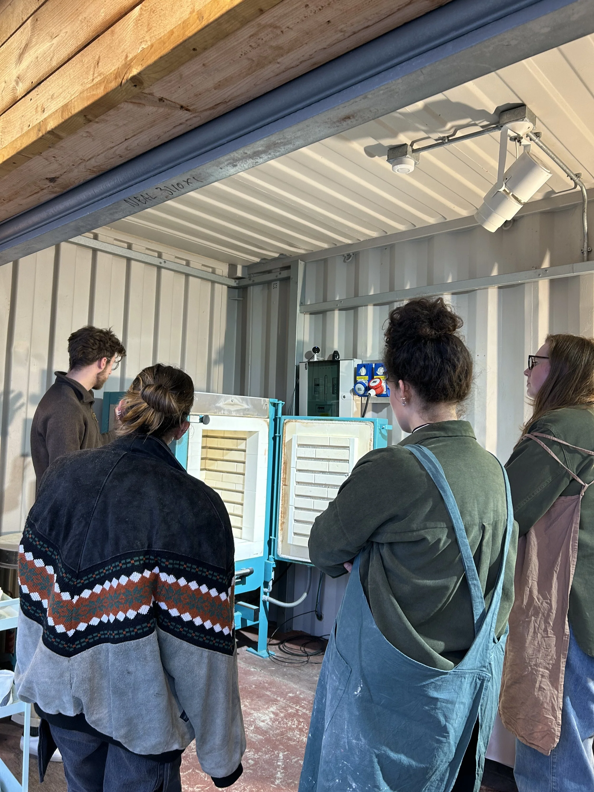 Group of four people observing a piece of scientific equipment indoors.