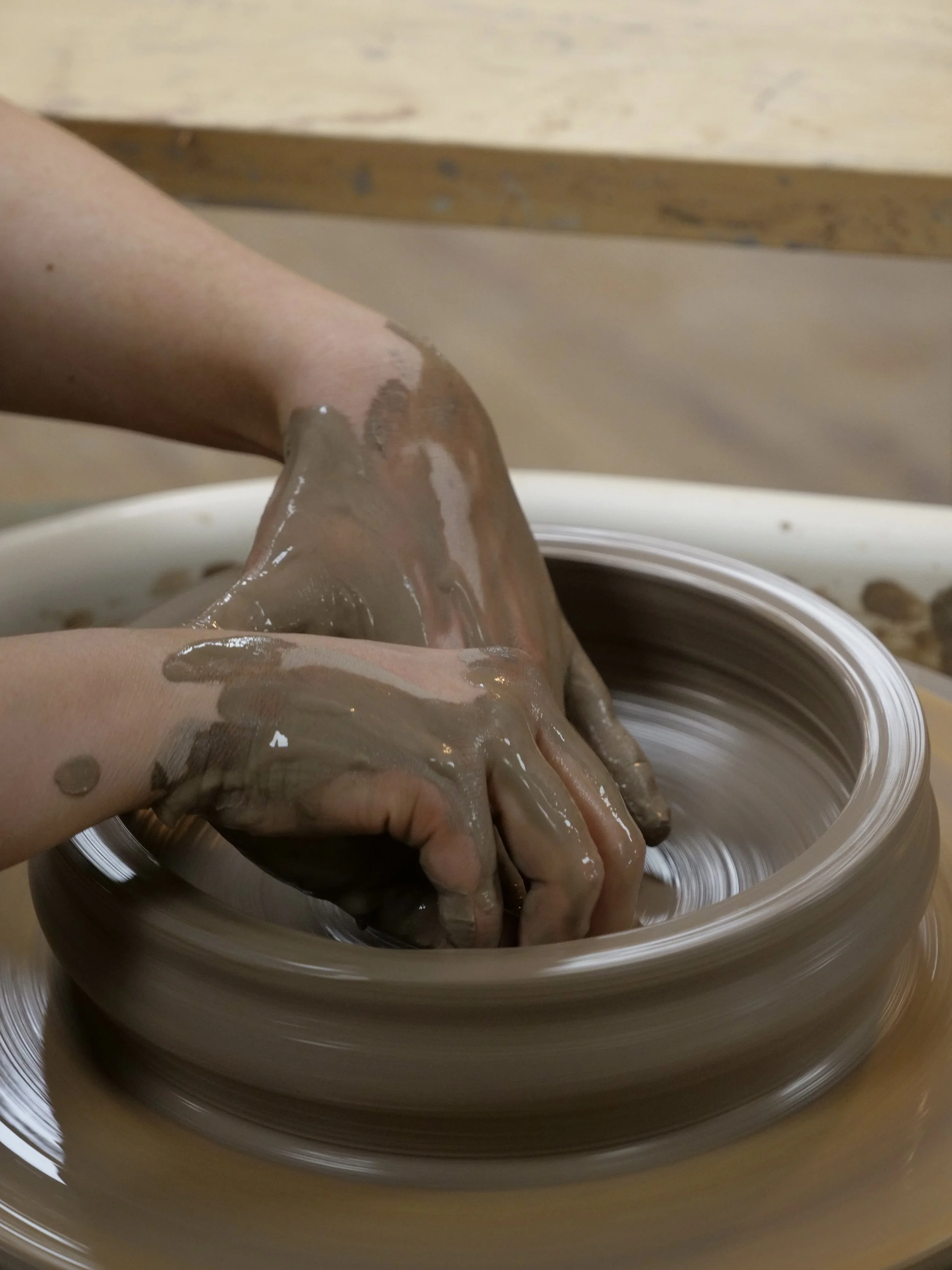 Person shaping clay on a pottery wheel.