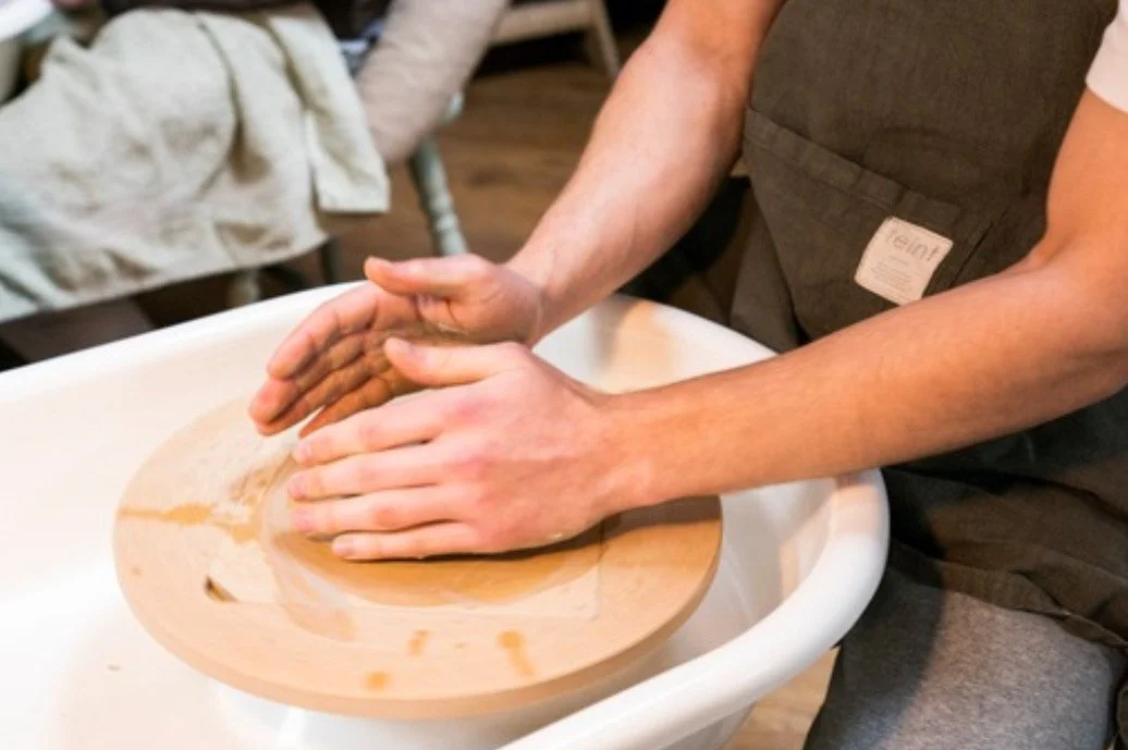 A person kneading dough on a wooden board in a white basin