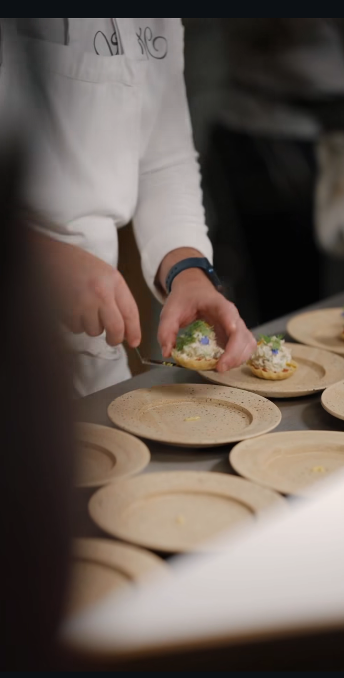 Person preparing decorated cookies on a table with empty plates.