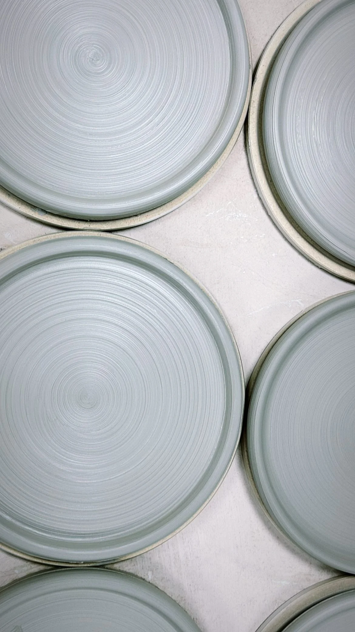Close-up of spinning pottery wheels with circular grooves, arranged on a flat surface, likely in a pottery studio.