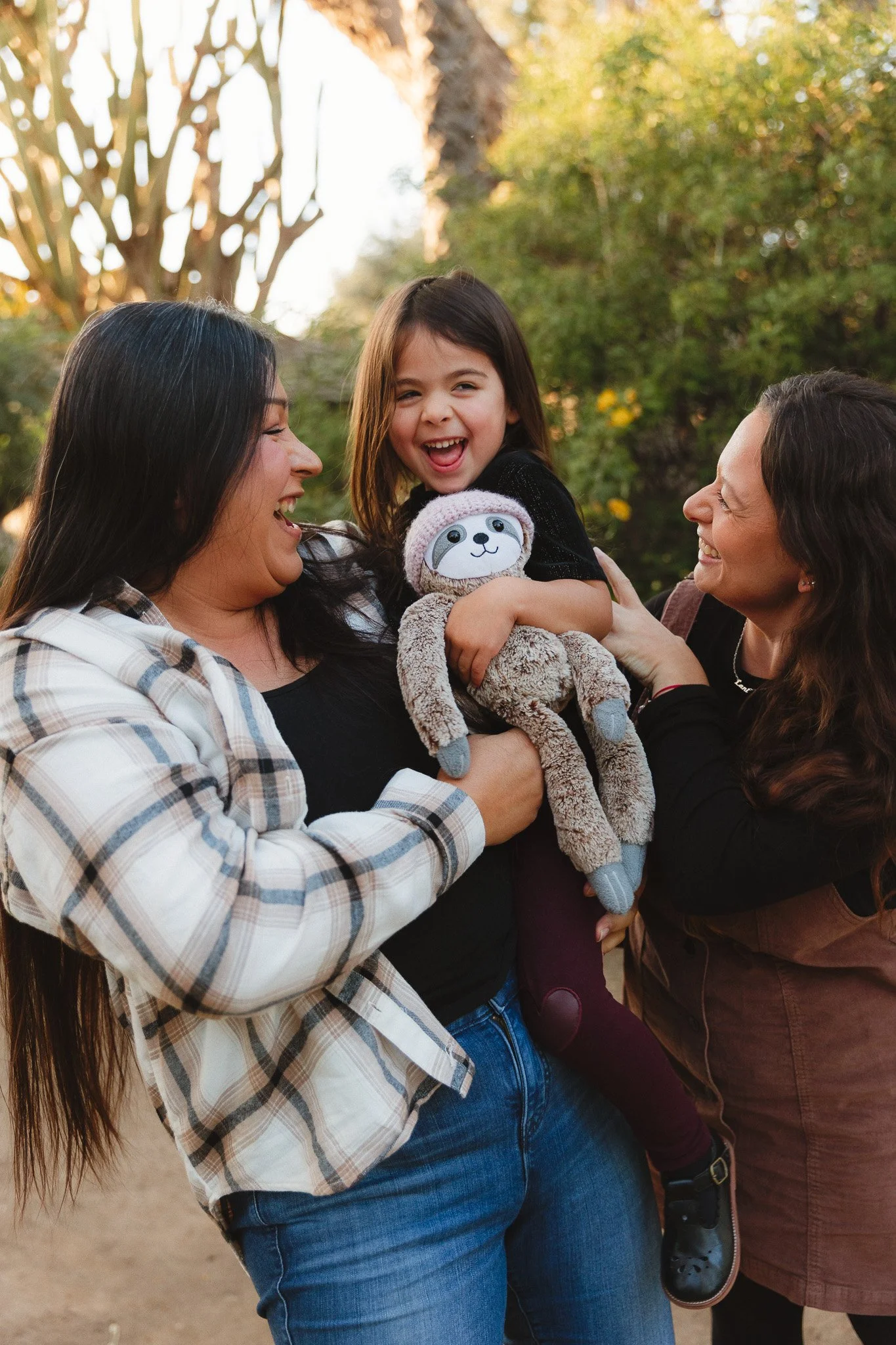 Orange County family photographer capturing two moms laughing with their child during an outdoor family photo session.