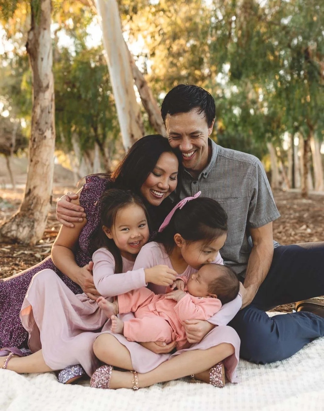 Parents and children cuddling on a blanket under eucalyptus trees at Serrano Creek Park in Lake Forest.