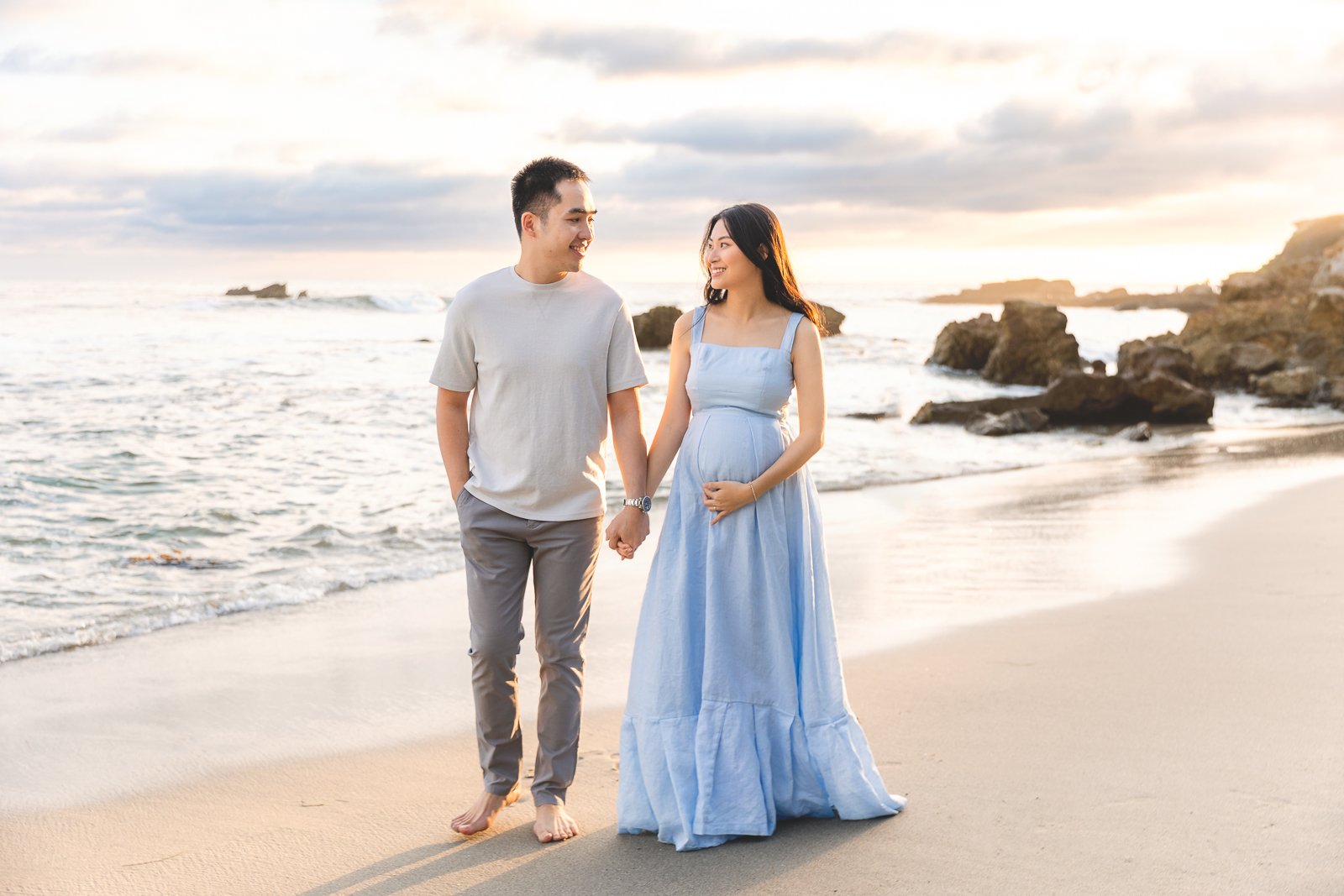 Orange County maternity photographer capturing a couple walking the shoreline at sunset