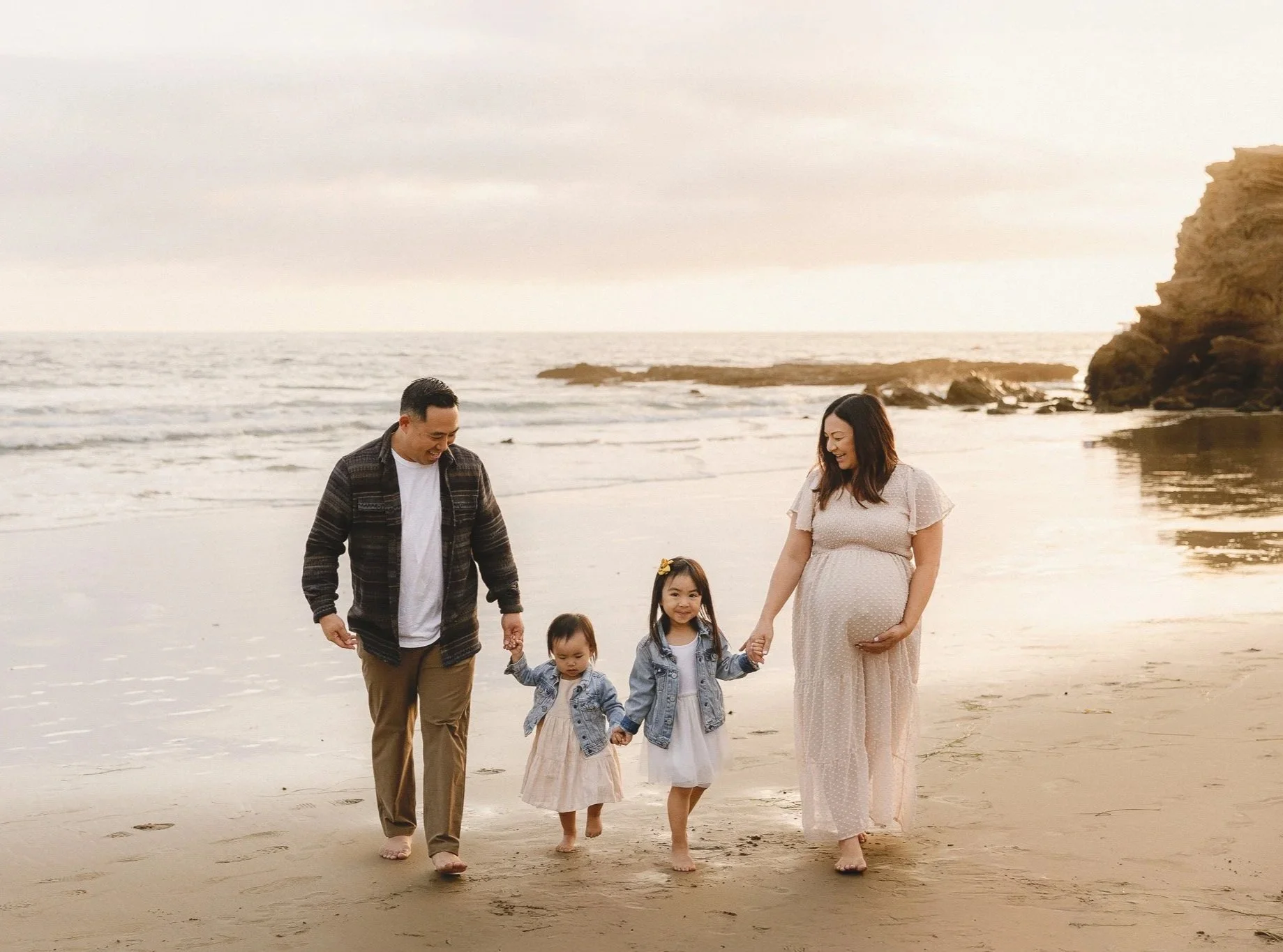 Orange County maternity photographer capturing a family walking on the beach with an expecting mom at sunset.