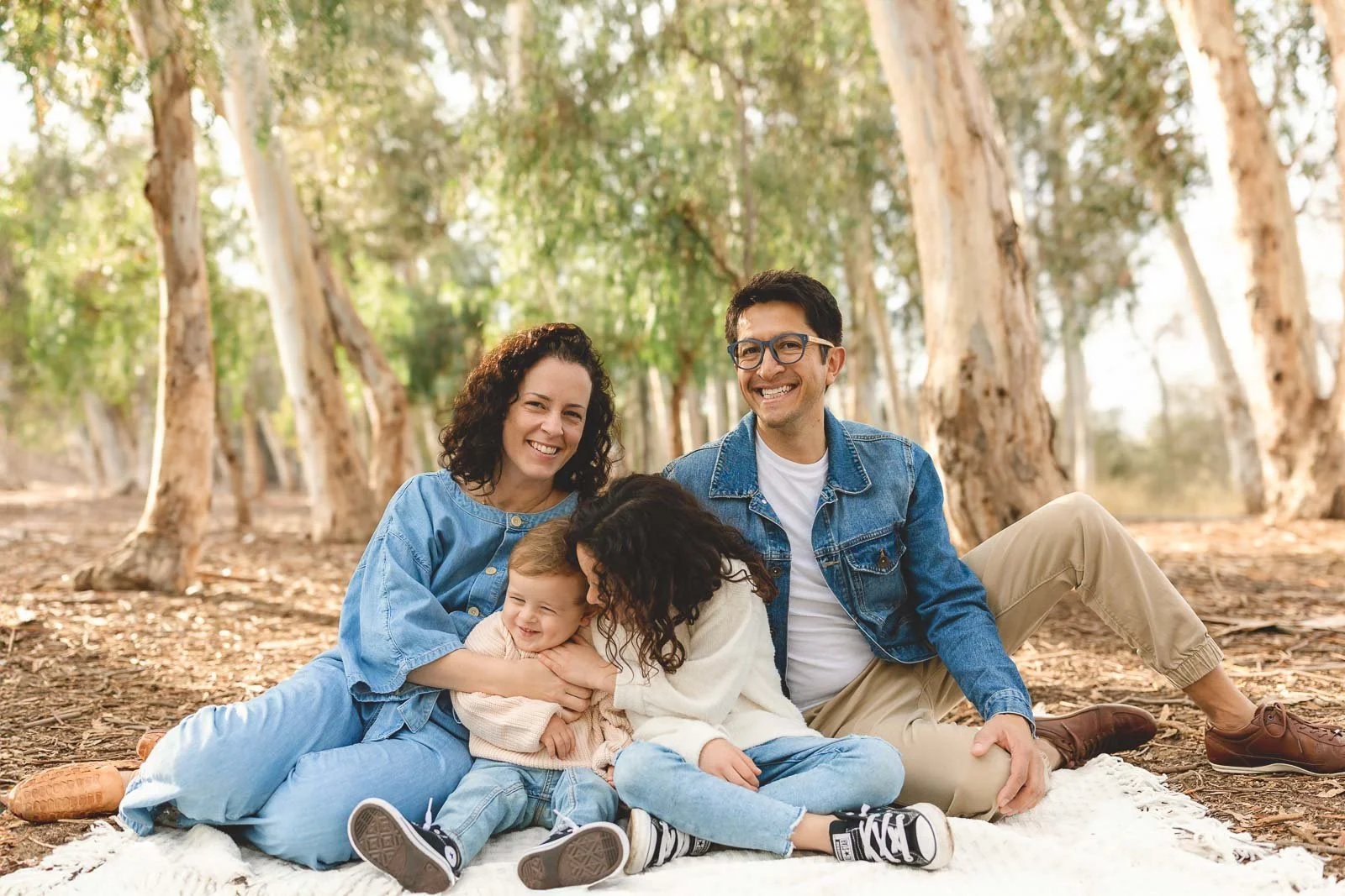 Family sitting on a blanket in the eucalyptus grove at Serrano Creek Park in Lake Forest, featured in this photoshoot location guide.