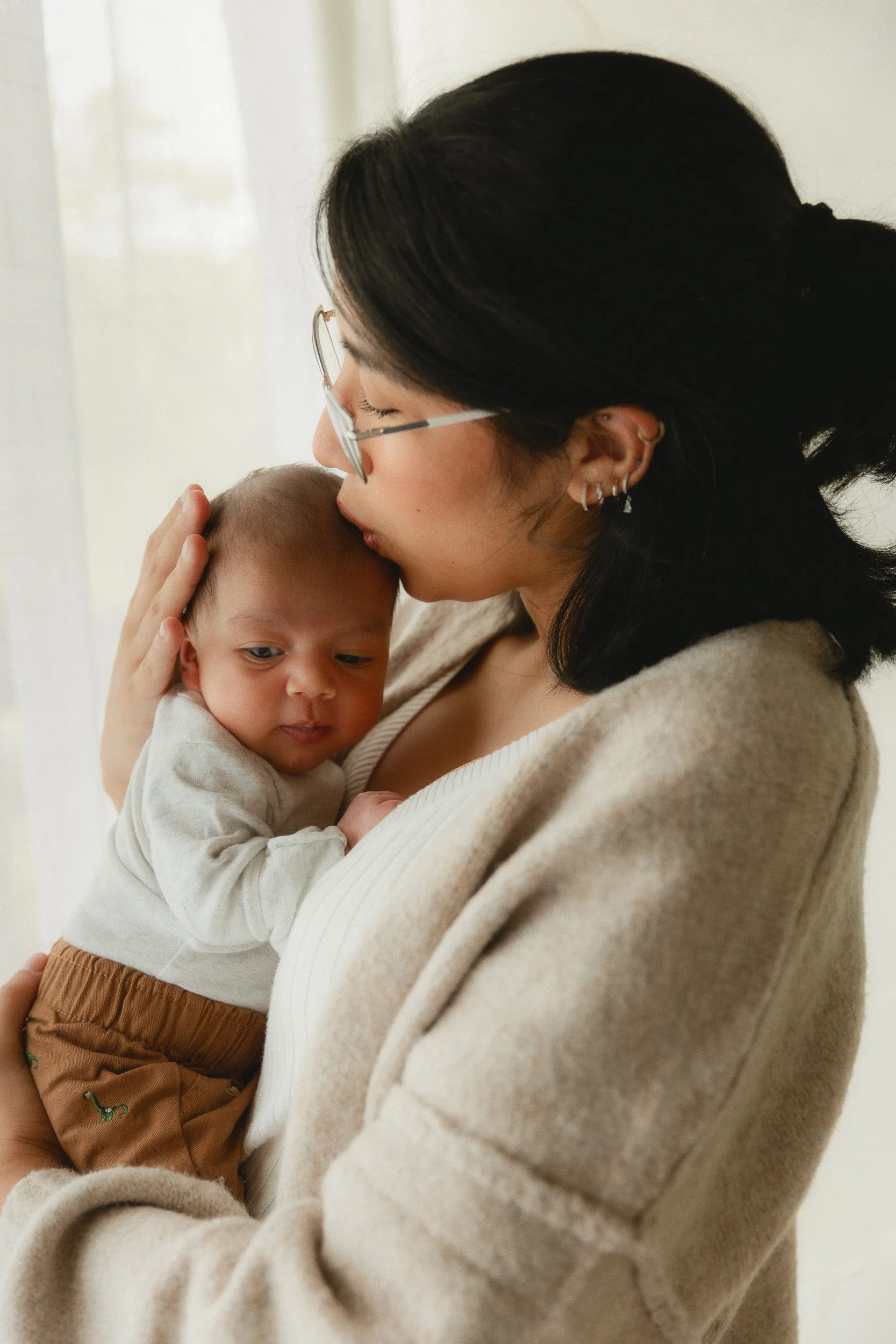 Mom snuggling her newborn baby during a studio newborn session in Huntington Beach, Orange County