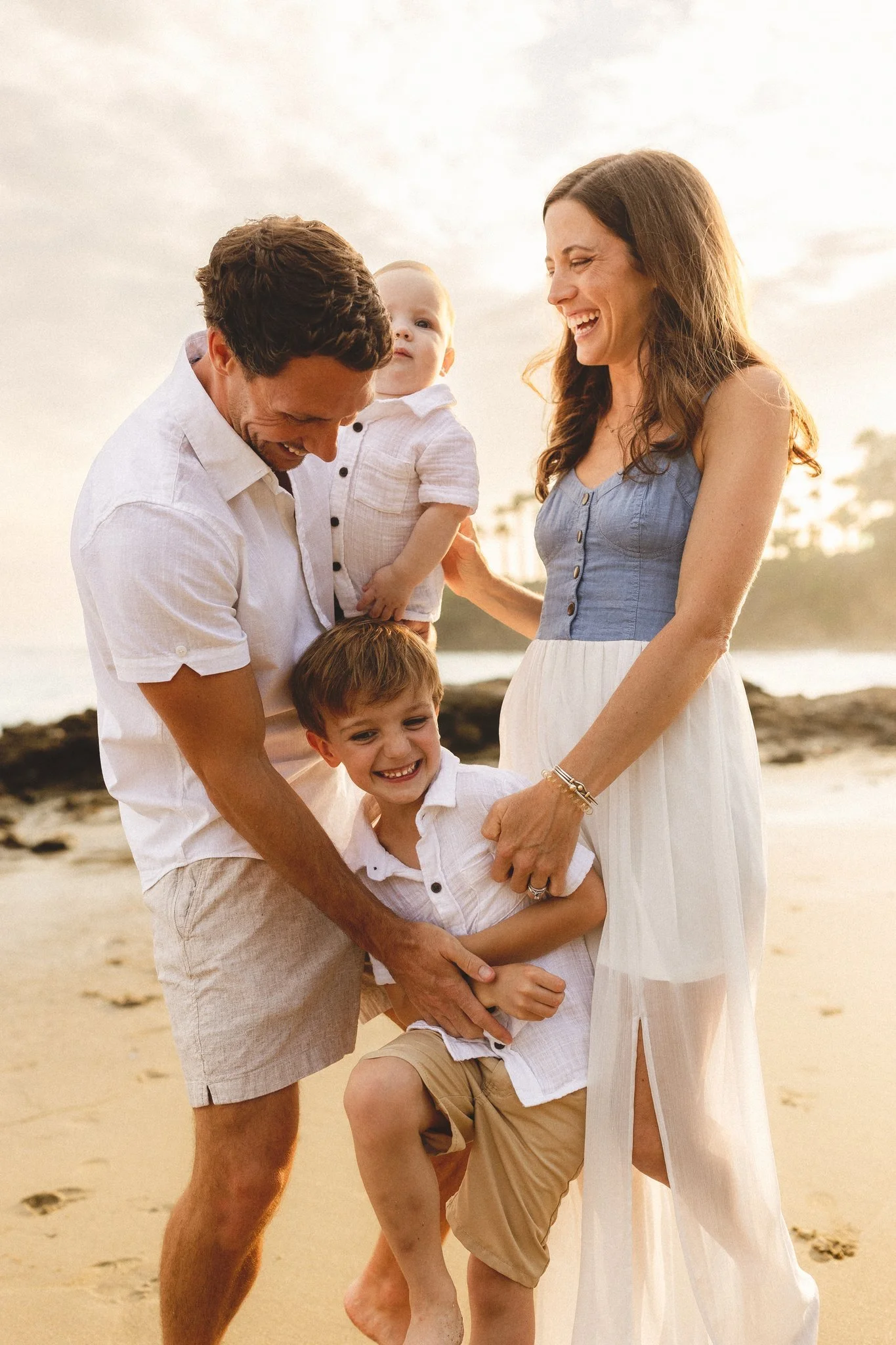Family laughing together on the beach during a golden hour session with an Orange County photographer.