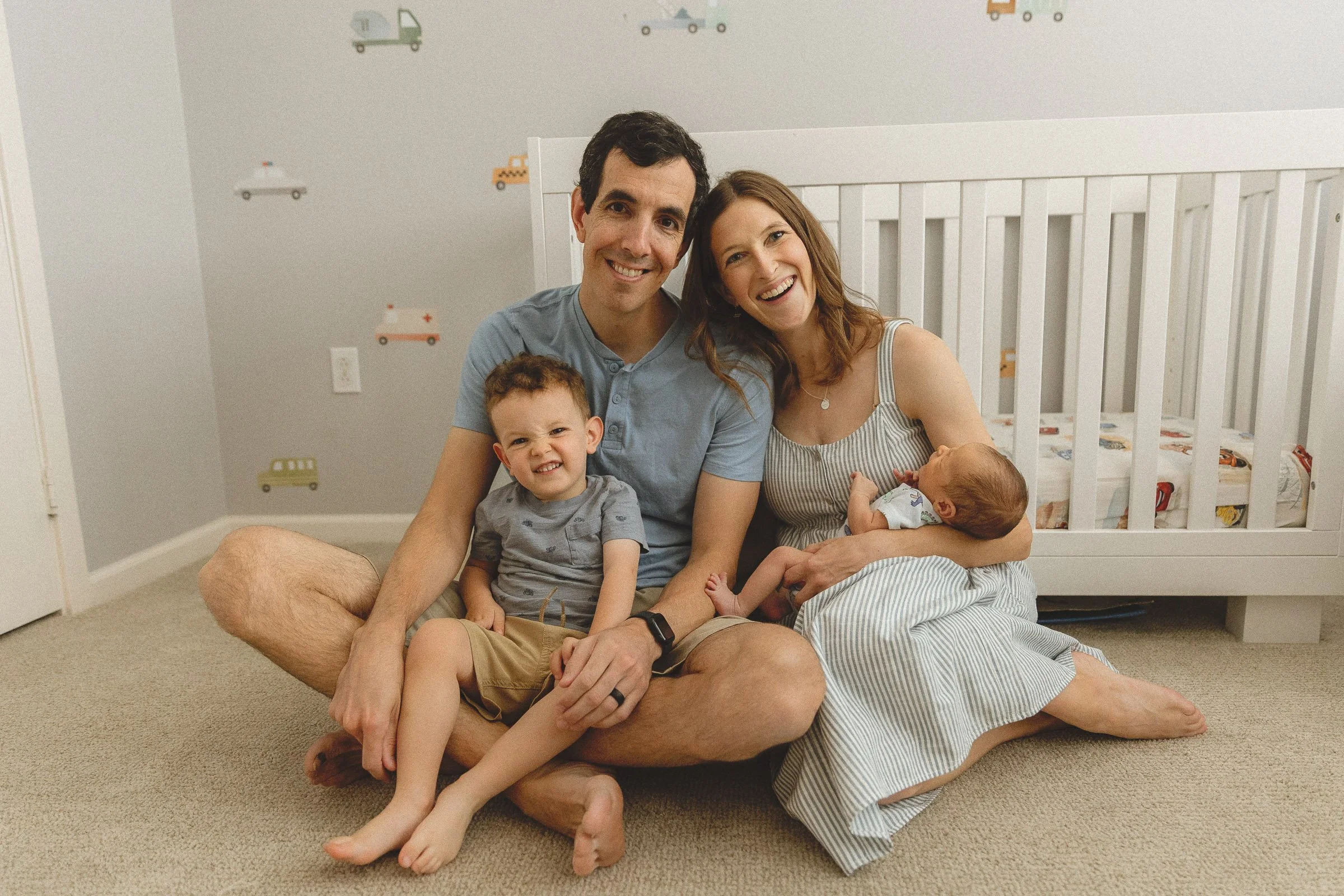 Family sitting together in the nursery with toddler and newborn during an in-home session.