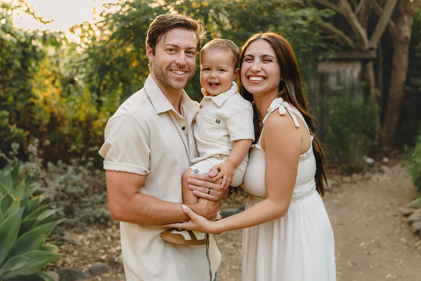 Parents holding their toddler close and smiling during an outdoor family session.