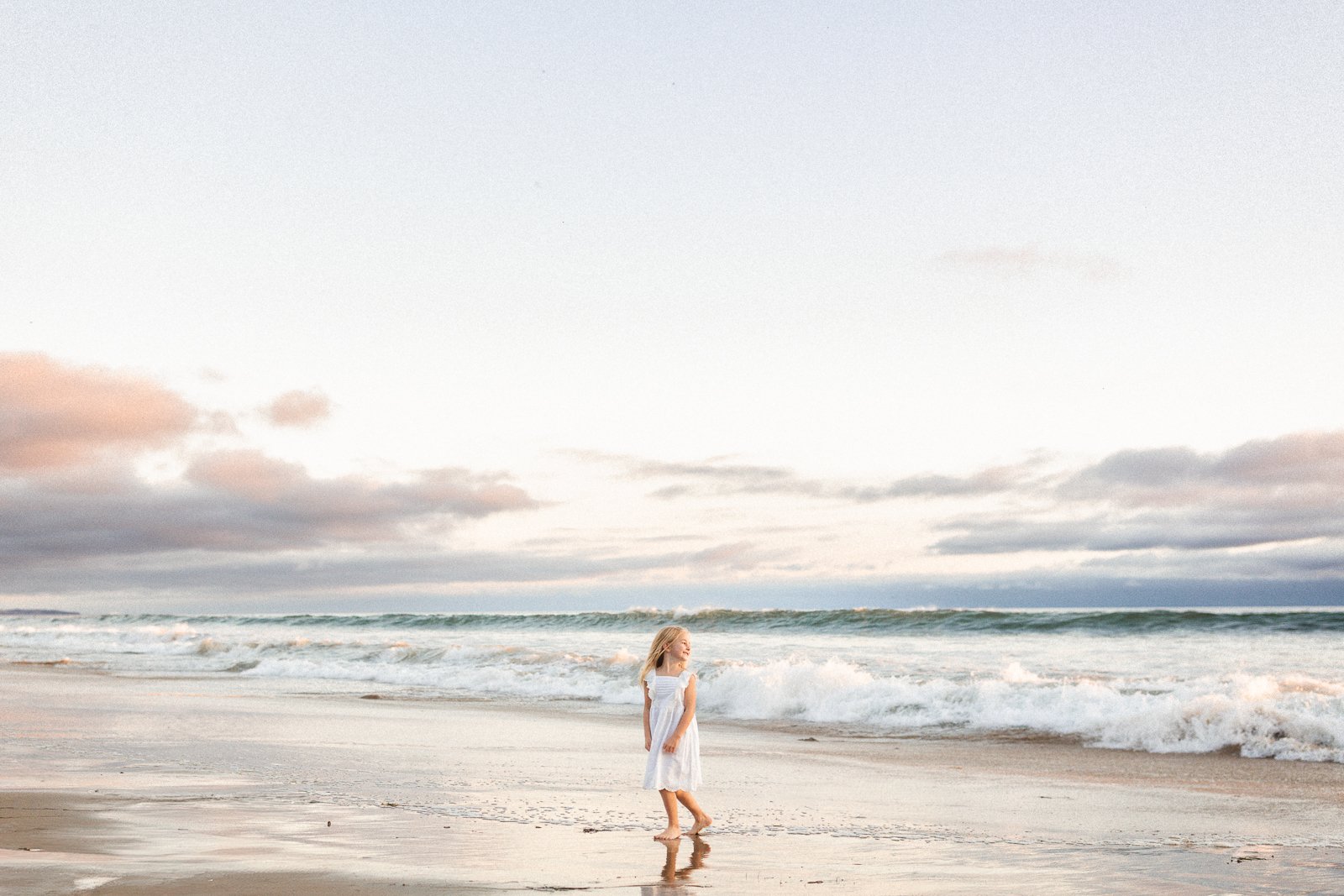 Child standing near the shoreline at Crystal Cove with waves and soft sunset light, featured in this photoshoot location guide.