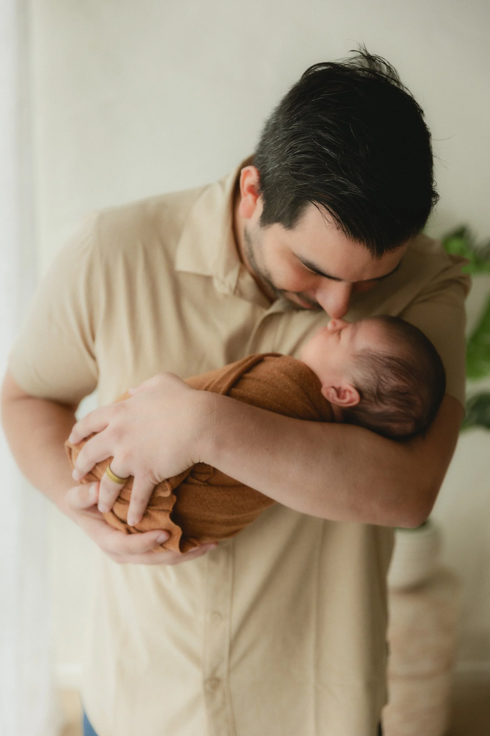 Dad holding his newborn baby close during a natural light studio session at Spark Studios in Huntington Beach