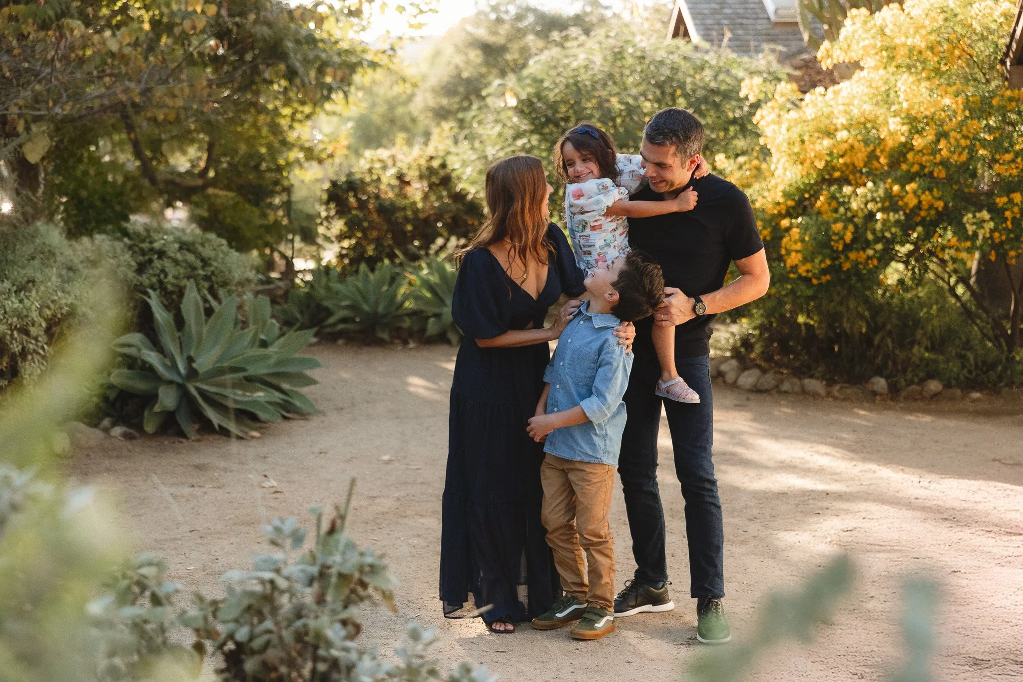 Family standing together outdoors while holding their kids in a relaxed, natural pose.