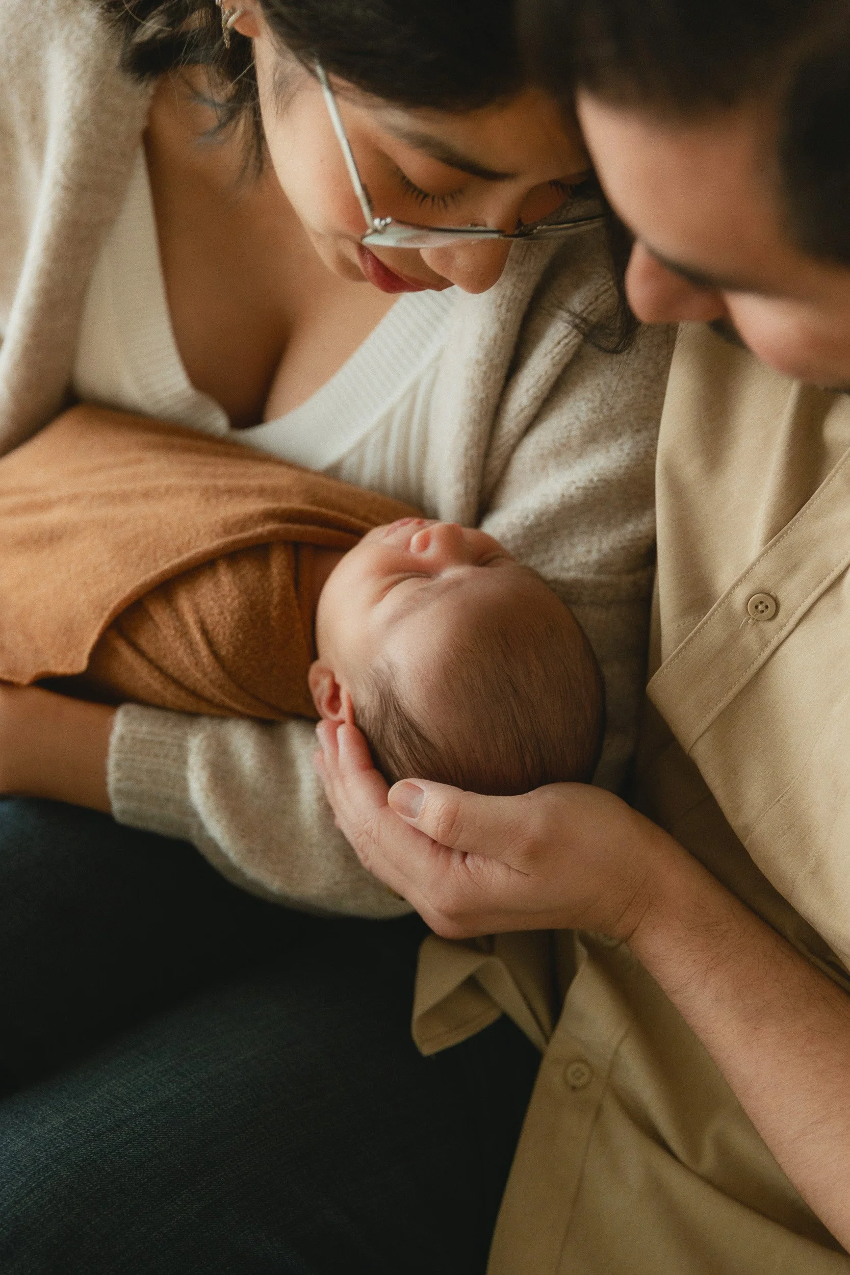 Close-up of mom and dad looking down at their newborn baby during a studio newborn session in Huntington Beach