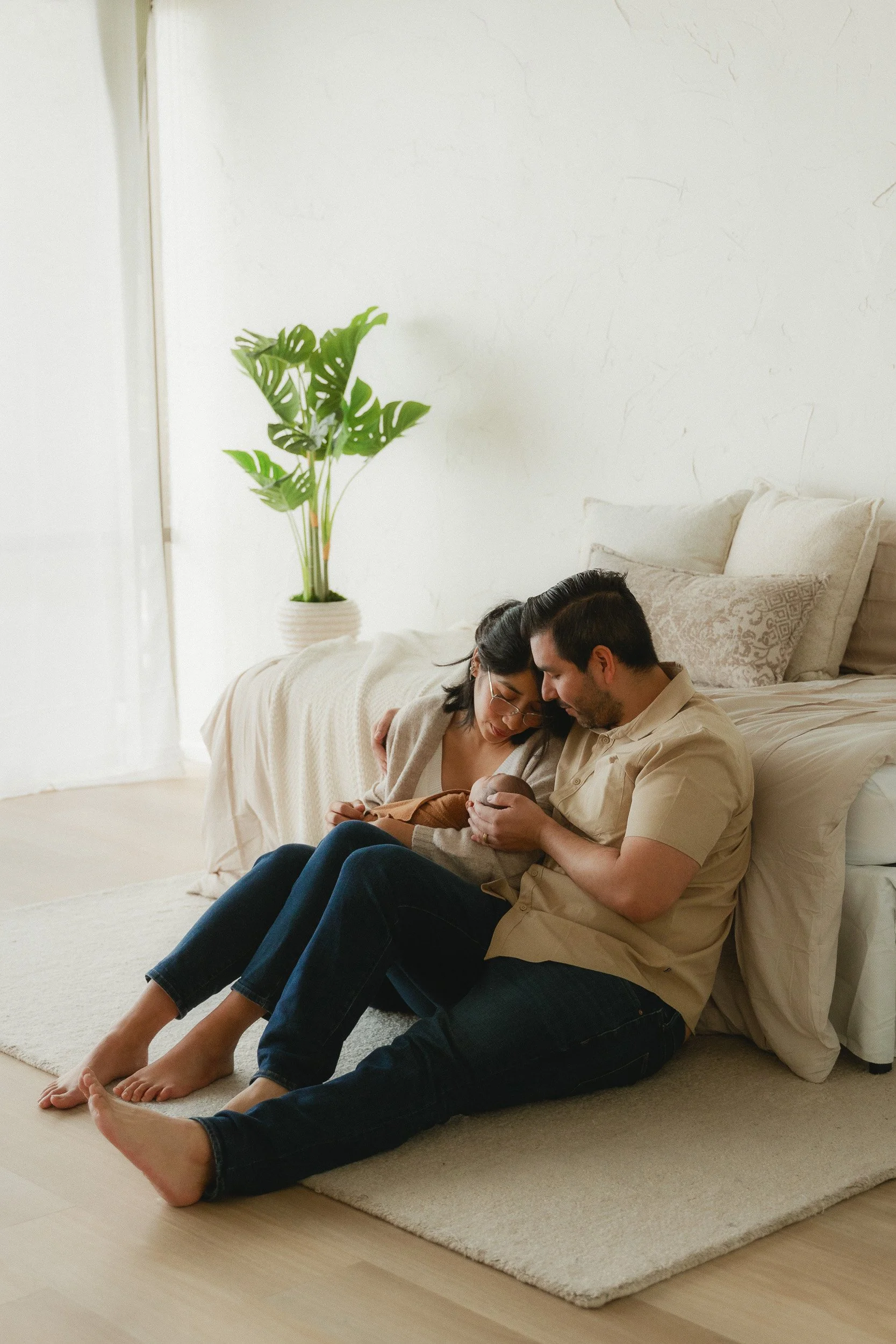 Parents sitting on the floor holding their newborn during a studio newborn session at Spark Studios in Huntington Beach