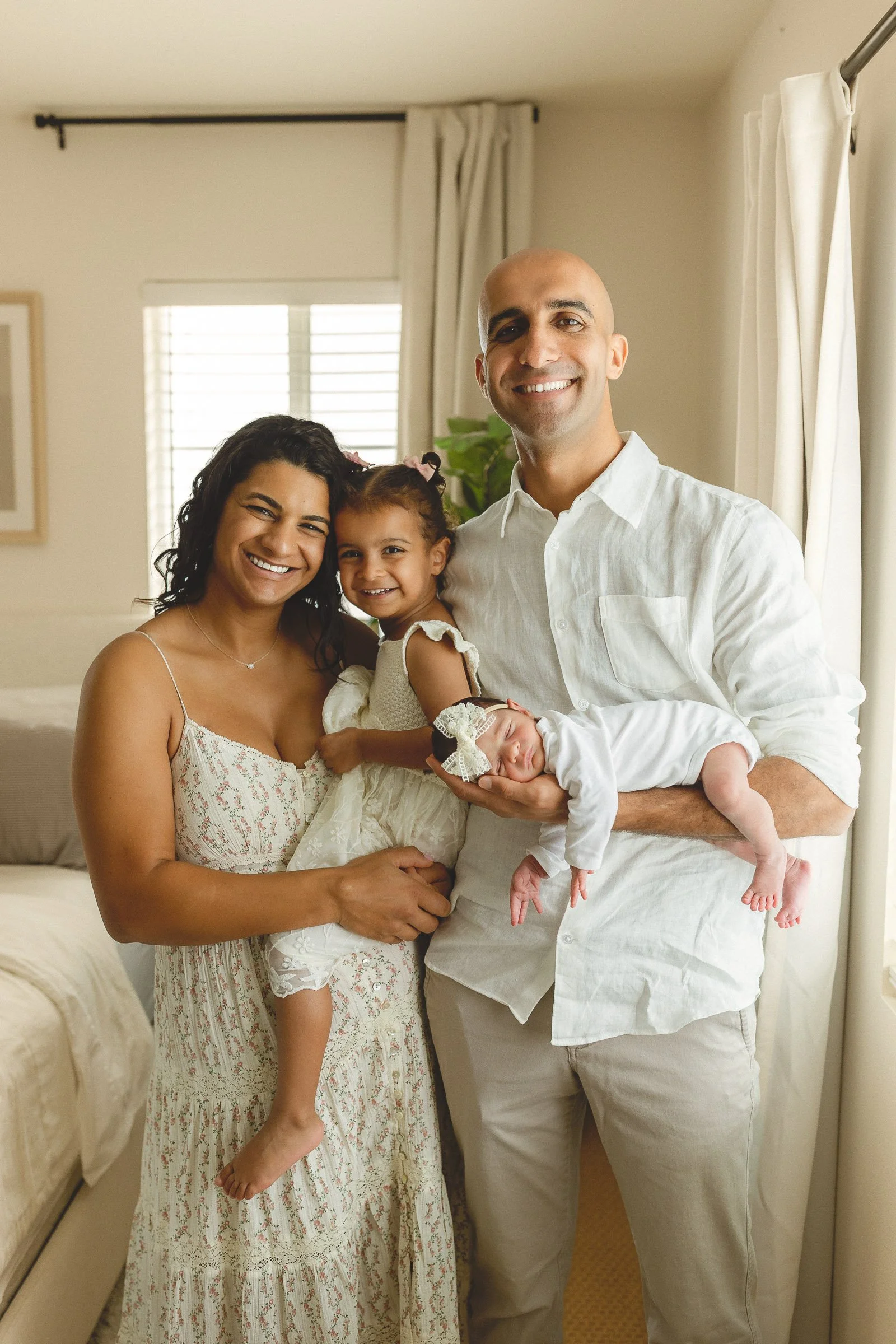 Family of four smiling in a bright home during a guided lifestyle session with an Orange County photographer.