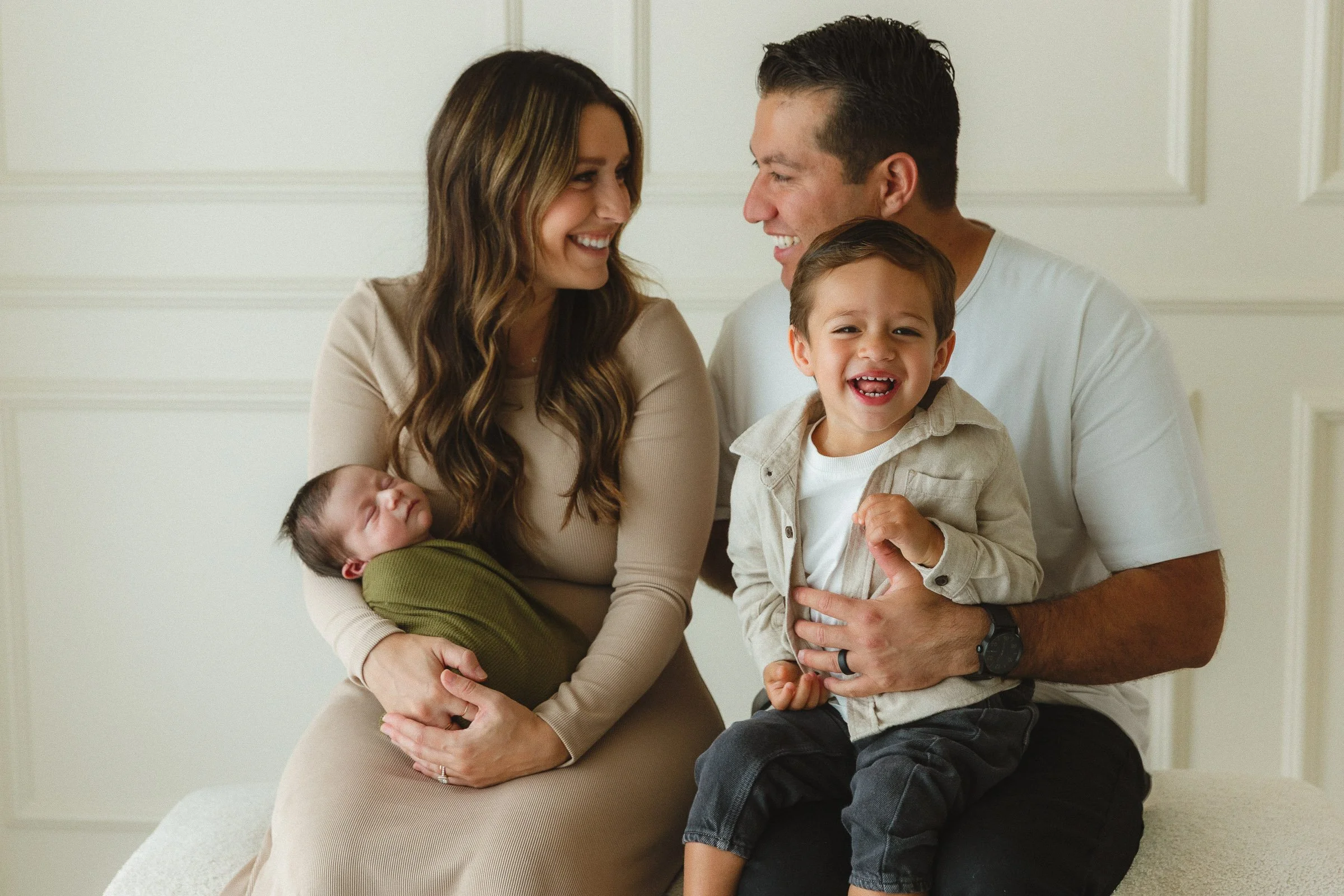 Family smiling together with their newborn and toddler during an in-home session with an Orange County newborn photographer.