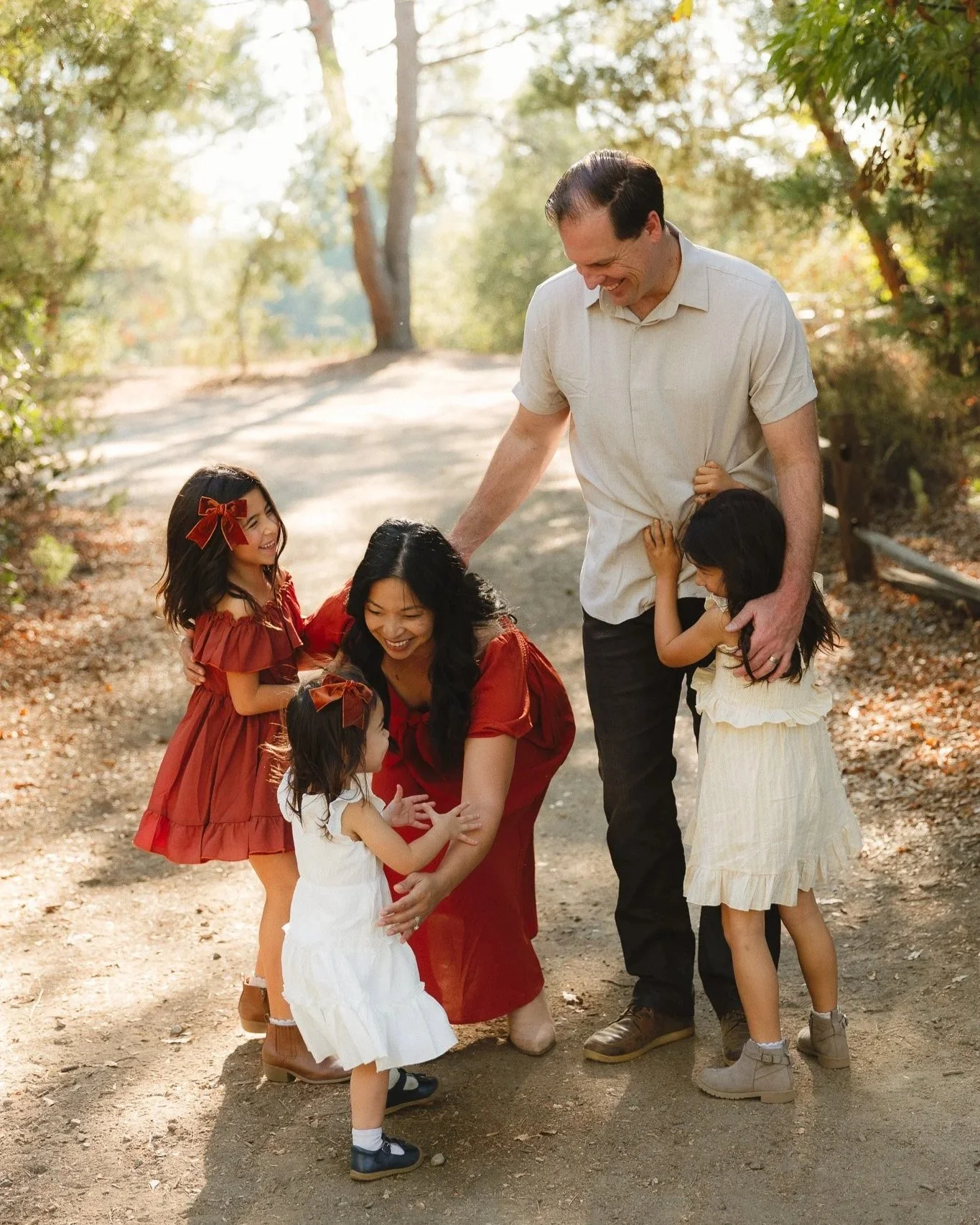 Orange County family photographer capturing parents laughing with their kids on a sunlit trail.