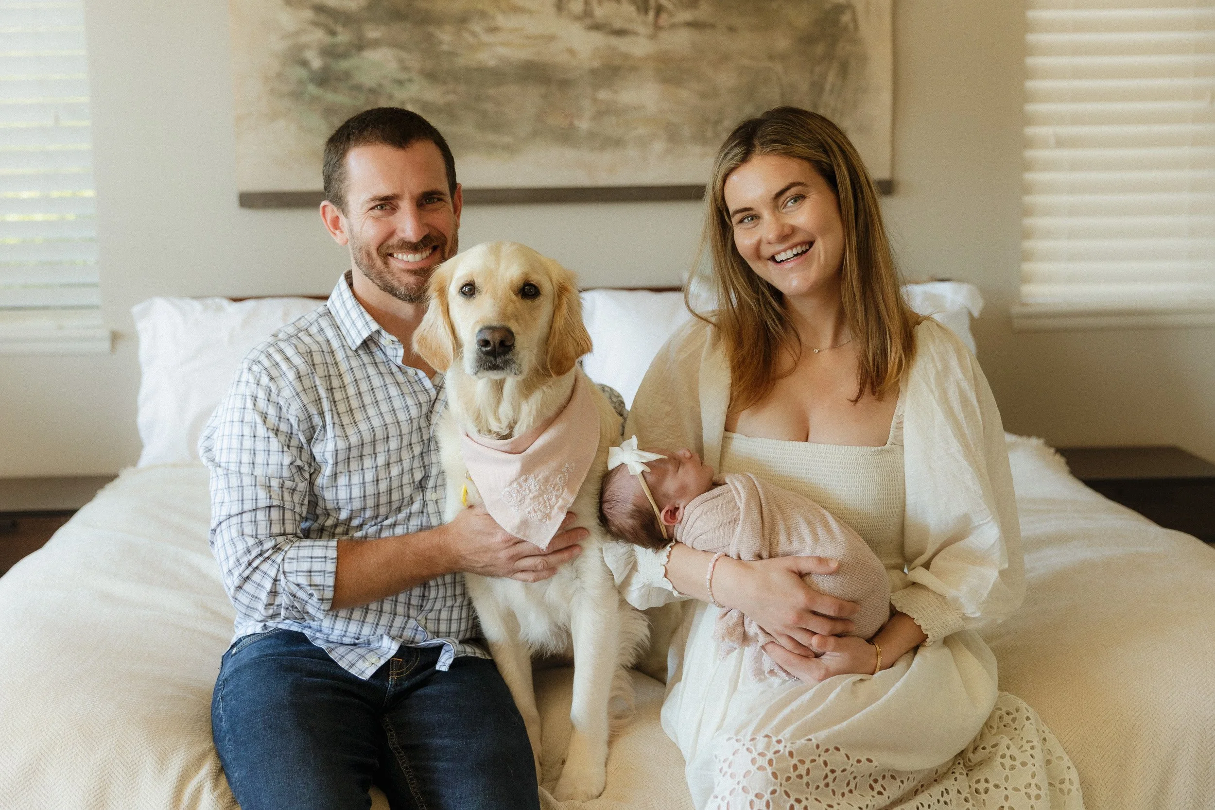 Family sitting on bed with their golden retriever and newborn during an in-home newborn session in Orange County