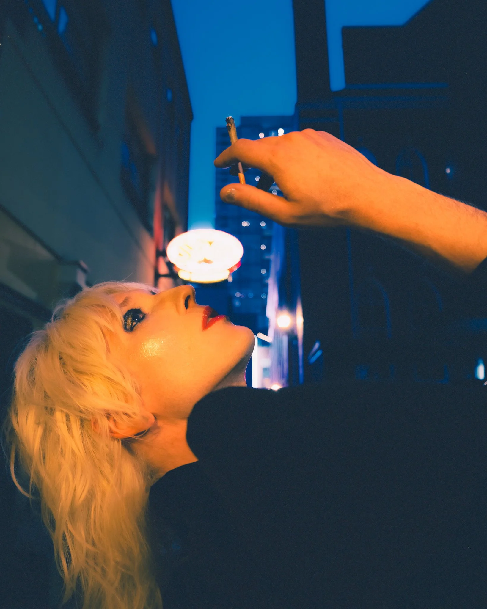 A woman with blonde hair lying down looks at the night sky, with her head tilted back and eyes open.