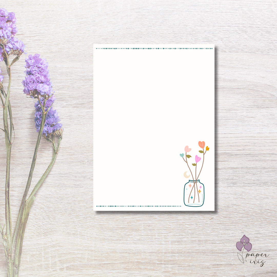 Blank paper with butterfly design on wooden background next to purple flowers.