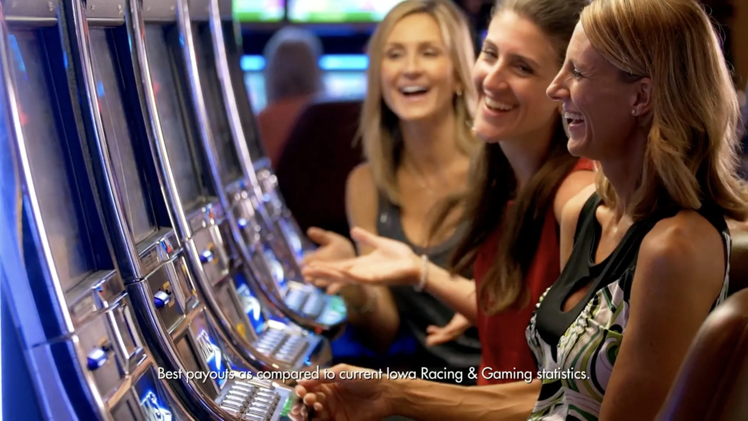 Three women playing slot machines in a casino, smiling and enjoying their time.
