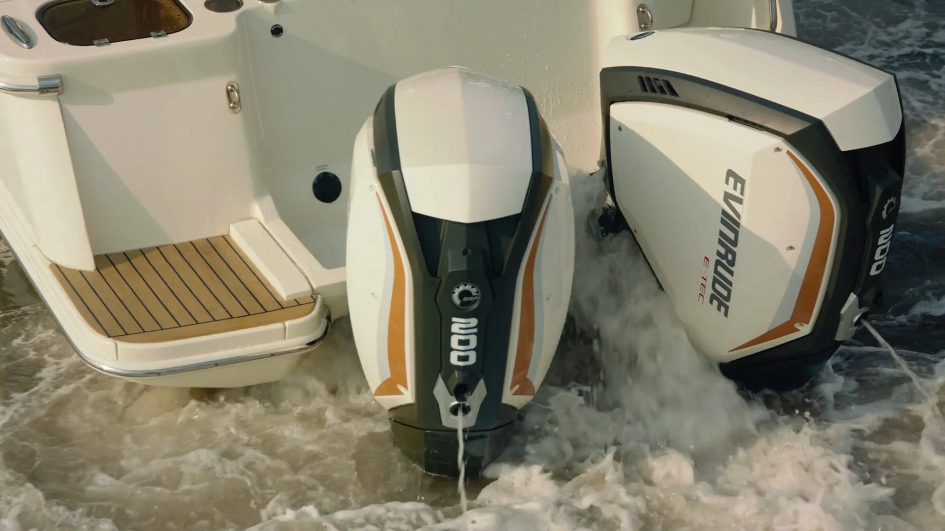 A boat with a wooden deck and two outboard motors, one smaller and one larger, labeled 'Evinrude E-TEC', on water with waves.