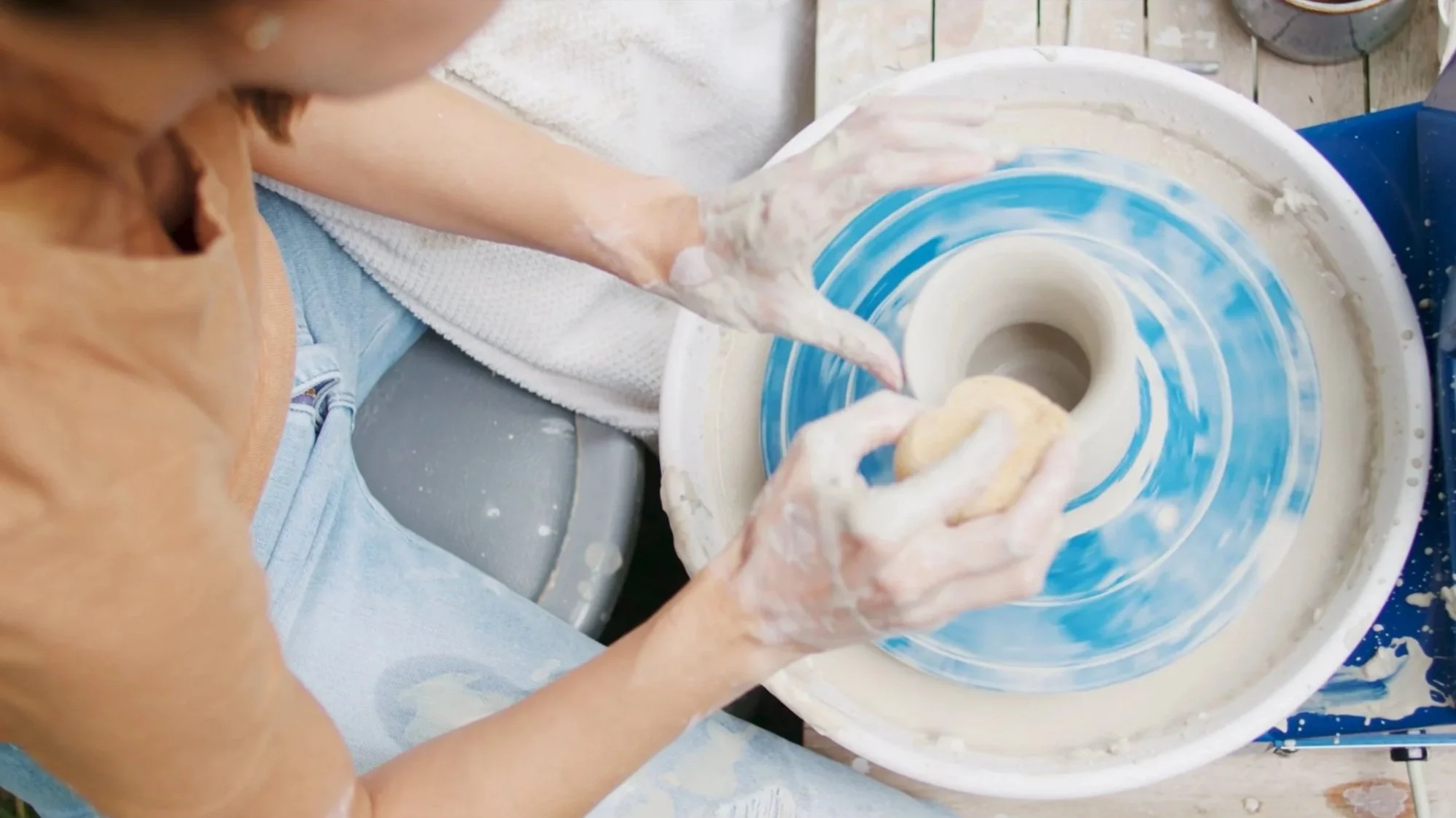 Person shaping clay on a pottery wheel in a pottery studio.