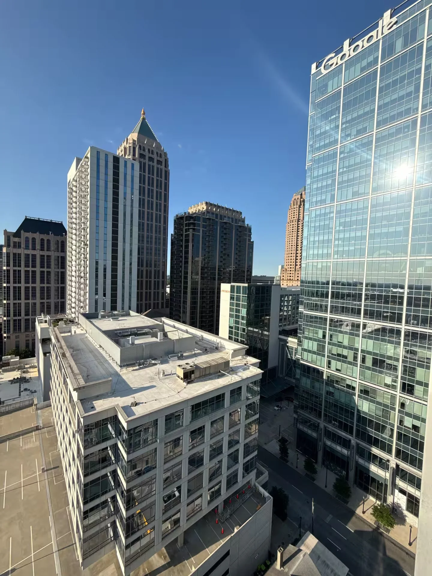 City skyline with high-rise office buildings including a glass building with the Google logo, under a clear blue sky.