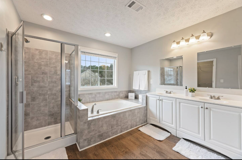Bathroom with a walk-in shower, bathtub, double vanity, mirror, and window