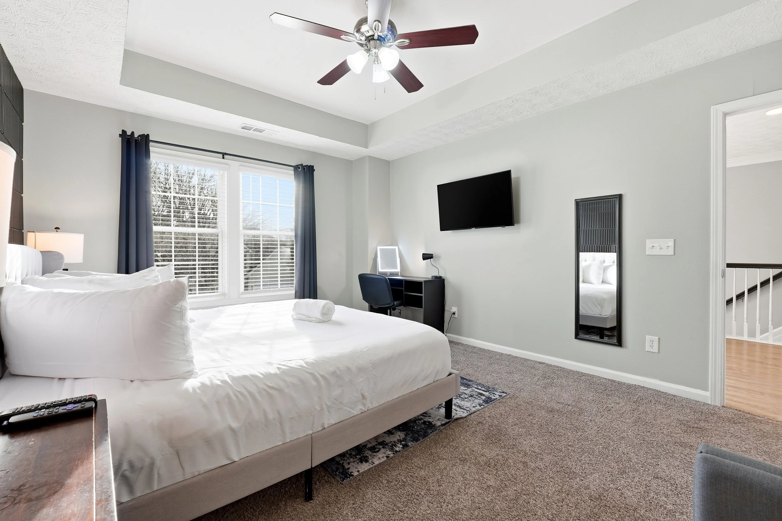 Enjoy this serene king retreat with warm lighting, a vanity mirror, comfortable lounge seating, blackout curtains, and a 50-inch TV for the perfect unwind