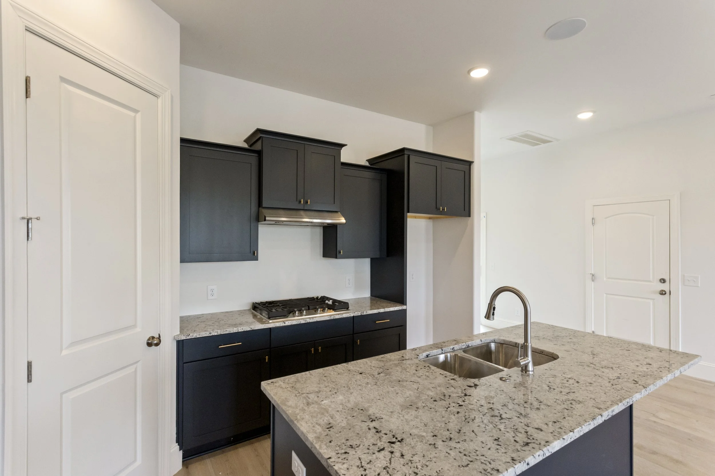 Modern kitchen with granite countertops, black cabinetry, and stainless steel appliances.