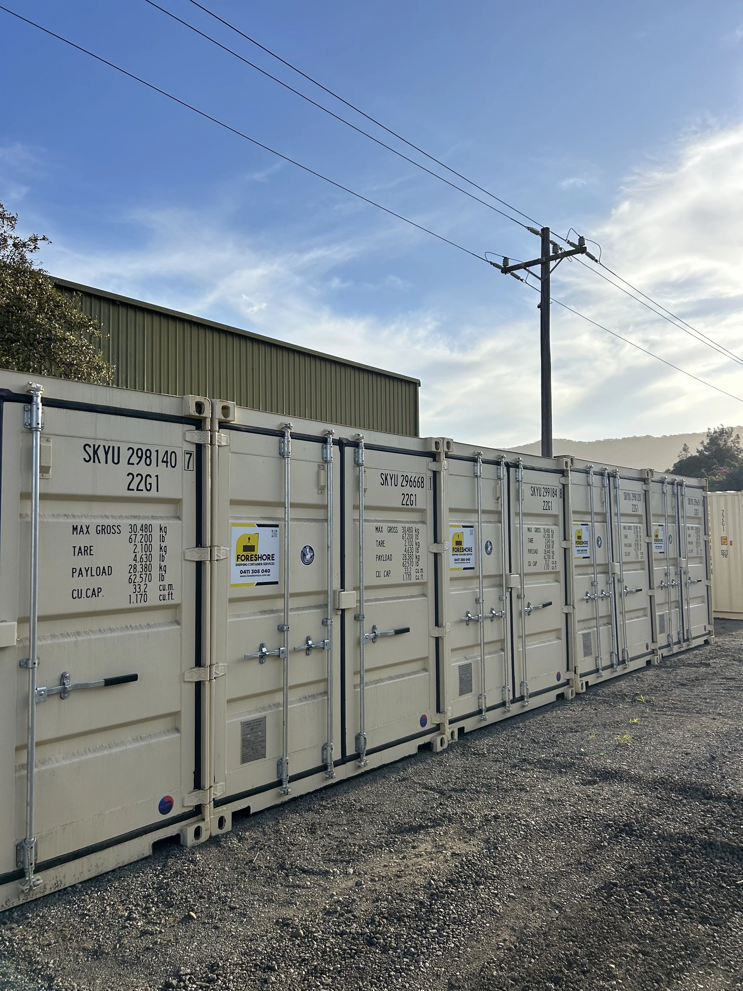 Shipping containers in a yard with a small black dog sitting in the foreground.