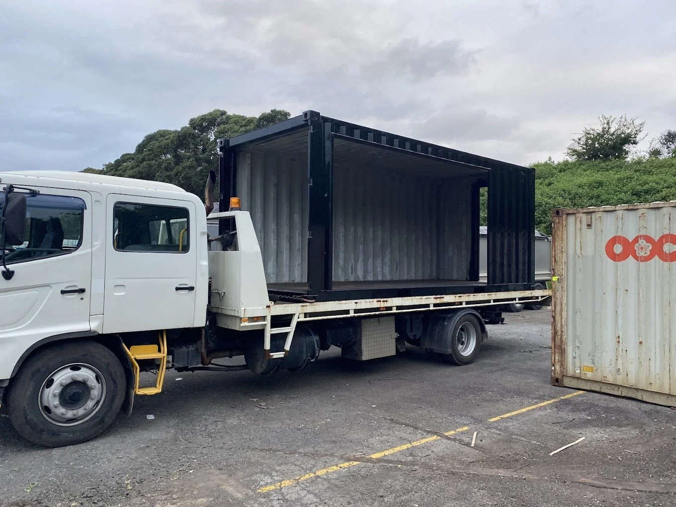 Flatbed truck with open shipping container in loading area