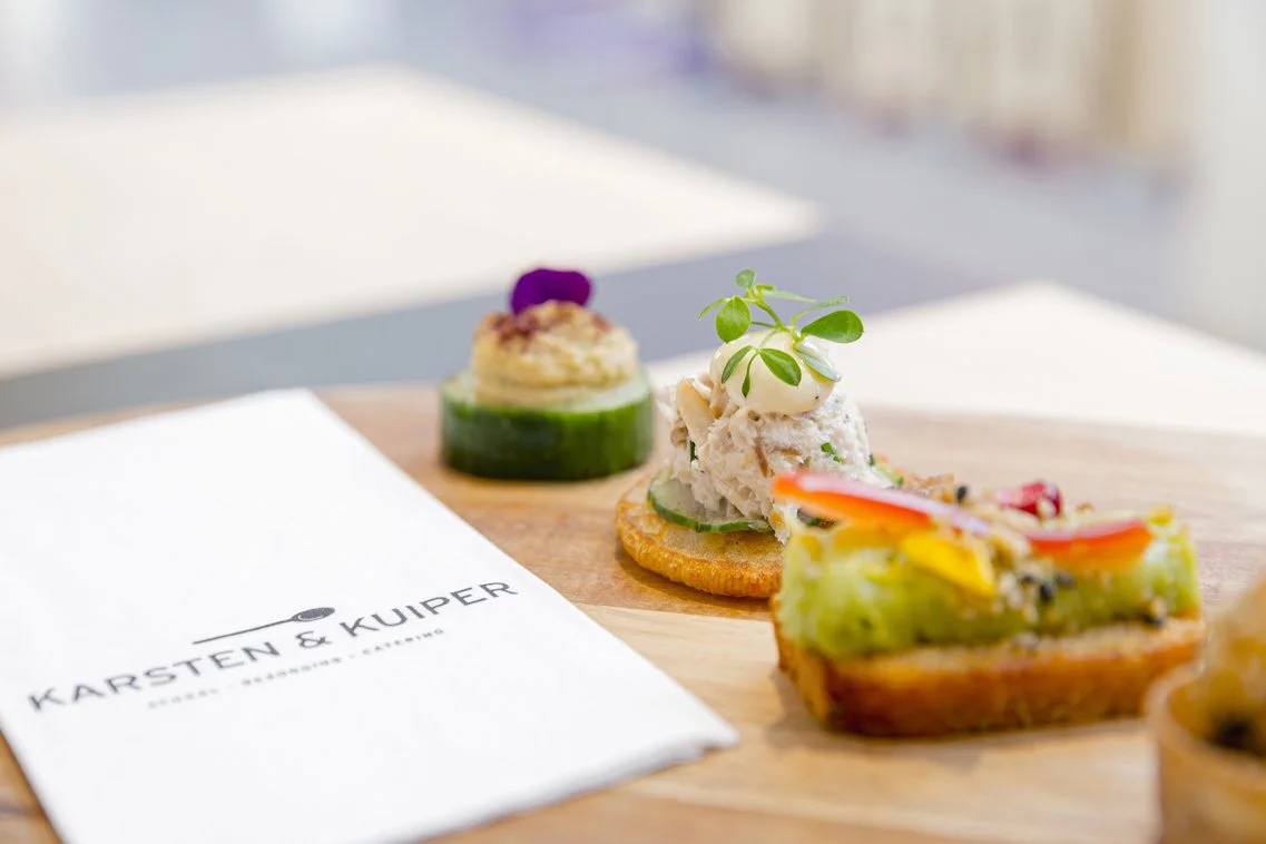 Gepresenteerde amuse met gerookte vis, groenten en een klein salade op houten bord.