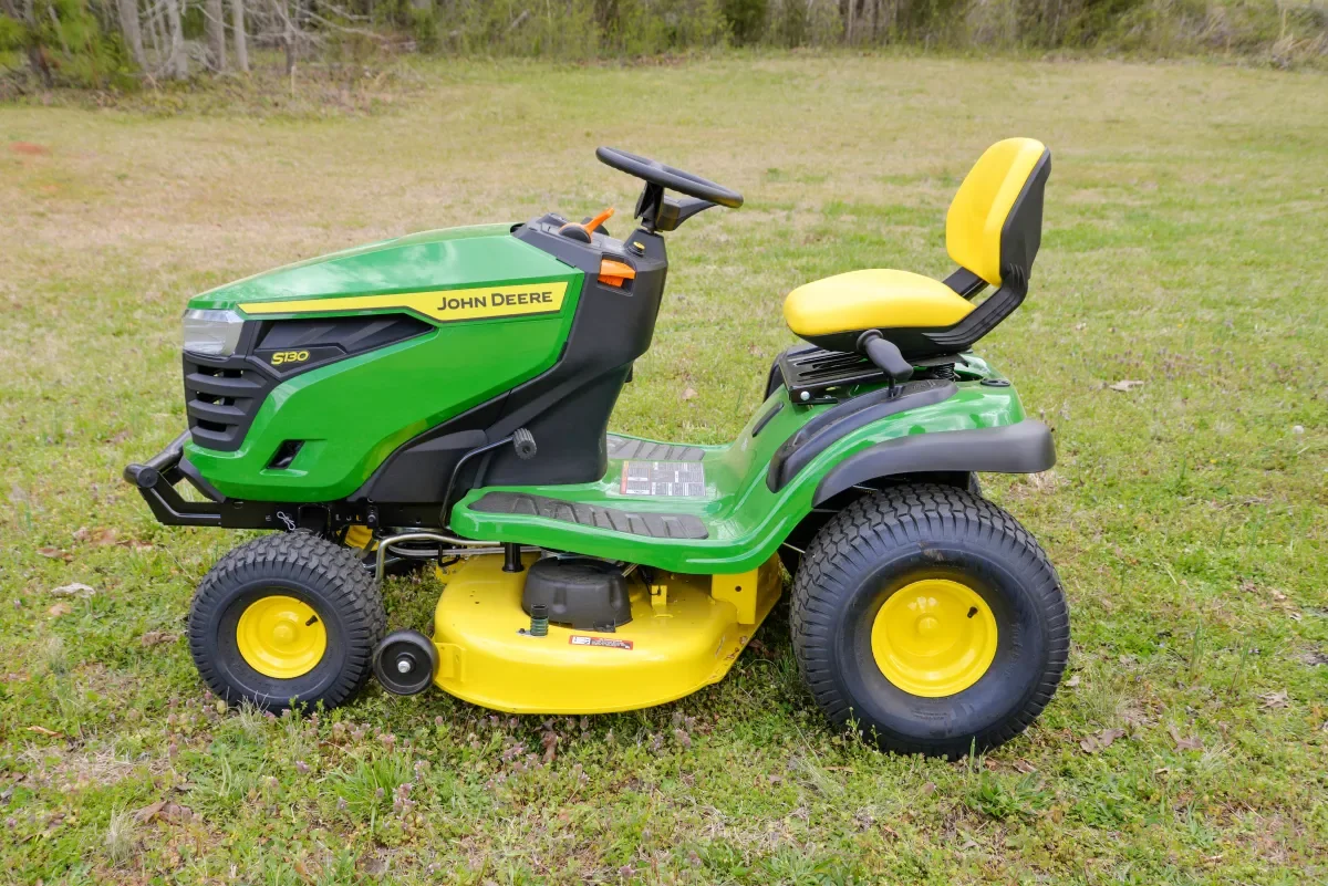 Green and yellow John Deere riding lawn mower on grass field